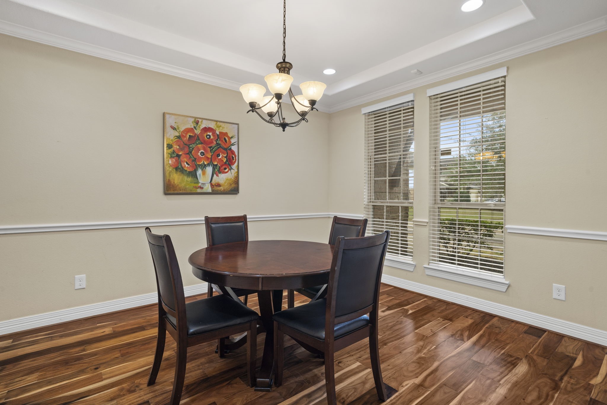 The well-appointed dining room features a tray ceiling with recessed lighting, elegant chair rail and crown molding, and large windows that fill the space with natural light.