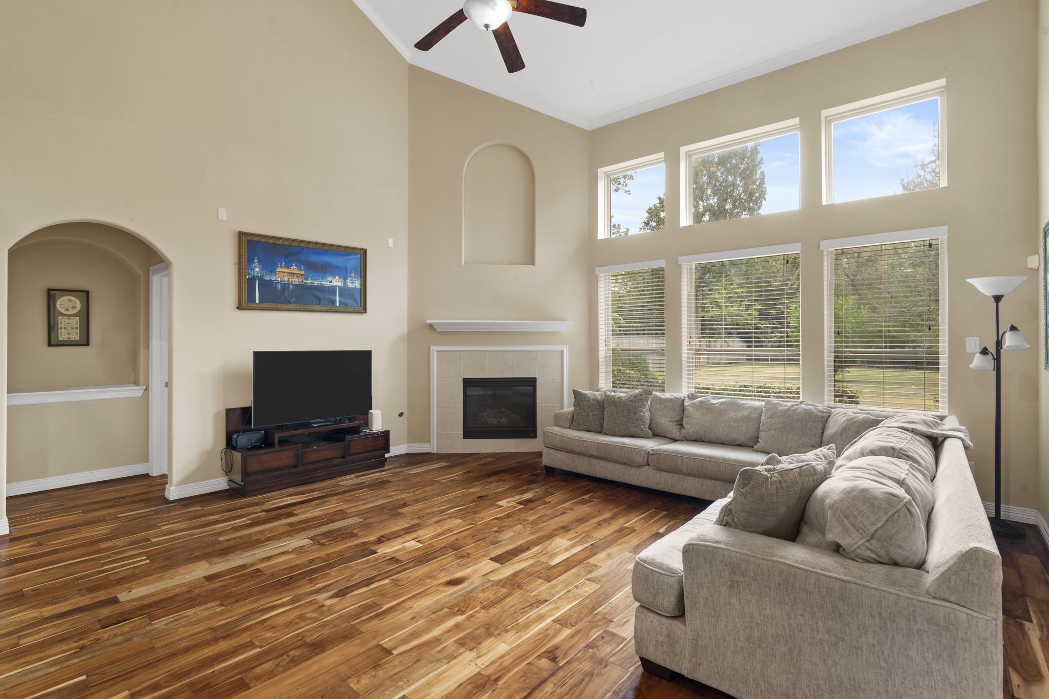 Light and airy living room featuring soaring two-story ceilings and floor-to-ceiling windows overlooking the private backyard.