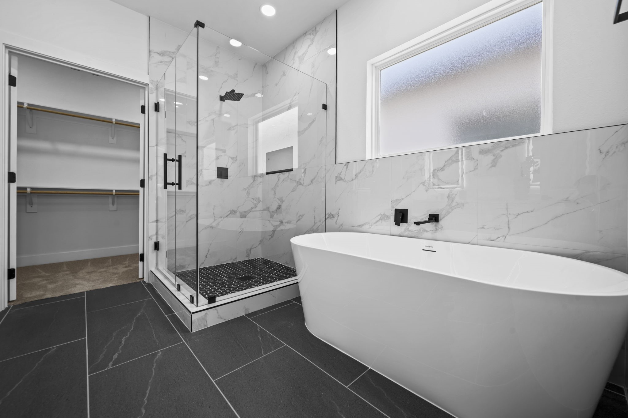 Gorgeous primary bathroom with marble floors, a walk in shower, and huge soaker tub connecting to the walk in closet.