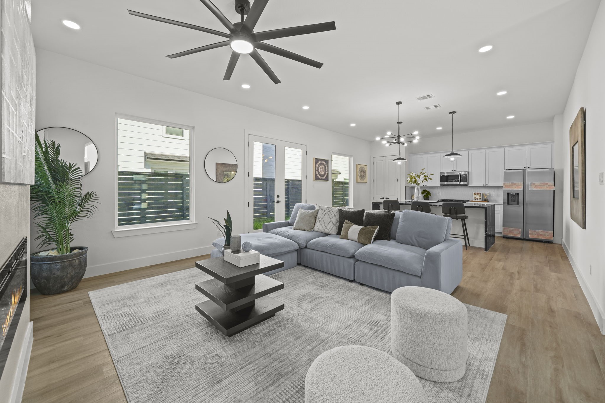 The living room and kitchen connect seamlessly with french doors leading to the back green space.