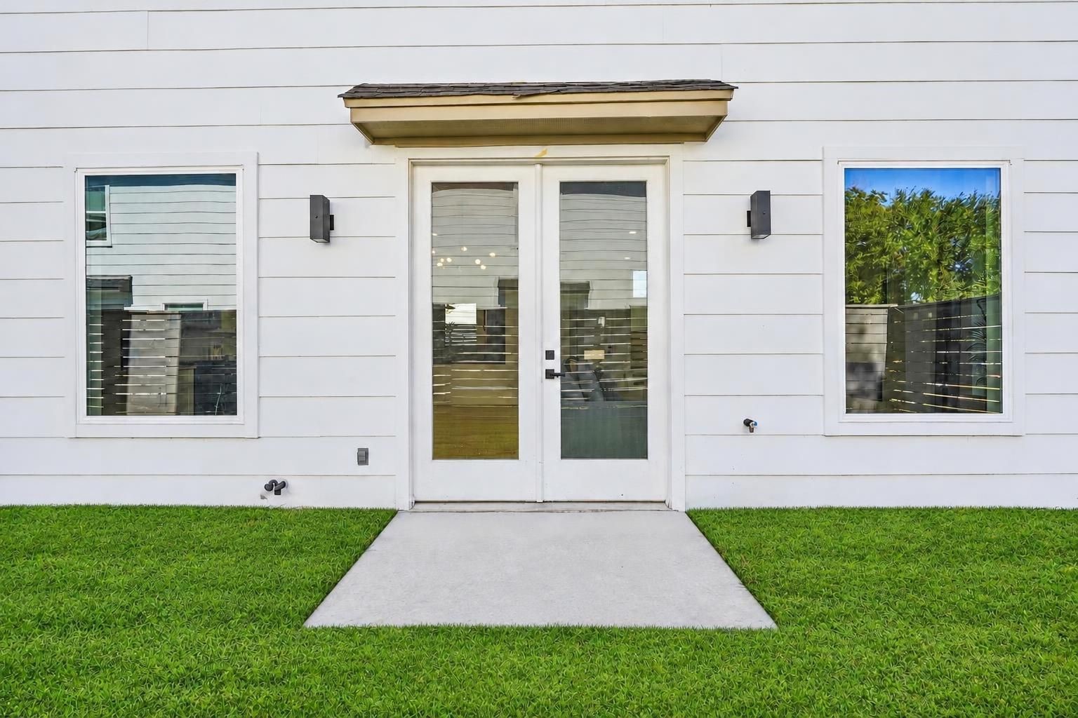 The back french doors leading to a partially fenced green space.