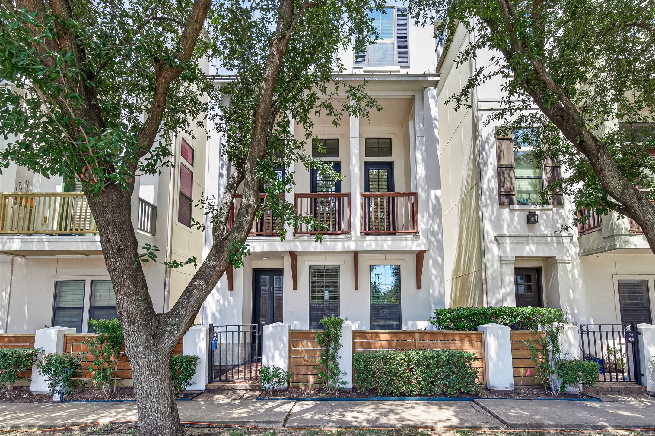 Charming three-story townhouse with elegant balconies and a welcoming front patio, nestled among mature trees for added privacy and curb appeal. Charming three-story townhouse with elegant balconies and a welcoming front patio, nestled among mature trees for added privacy and curb appeal.