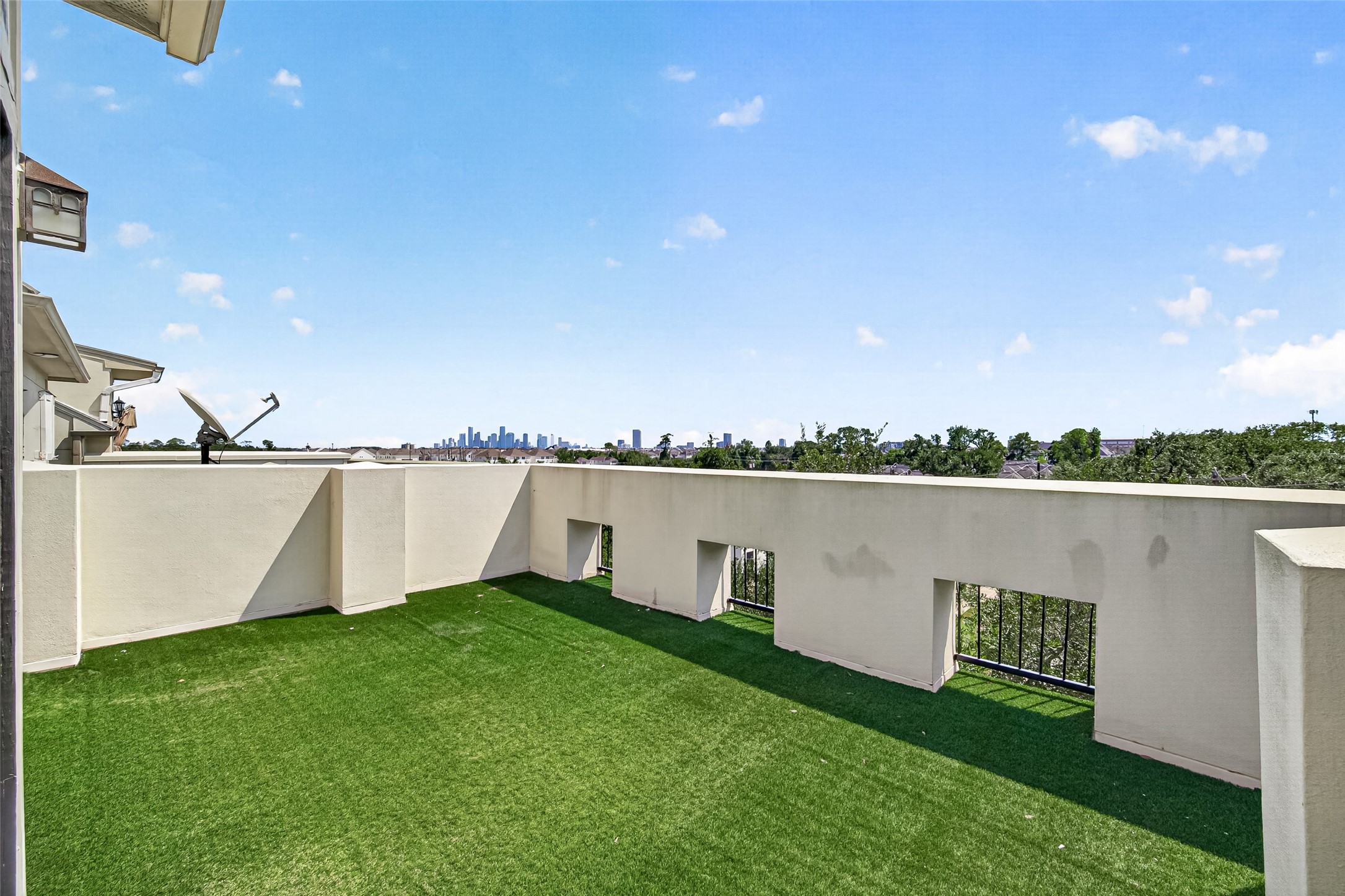 Expansive rooftop terrace with lush green turf offers stunning city skyline views, perfect for outdoor relaxation and entertainment.