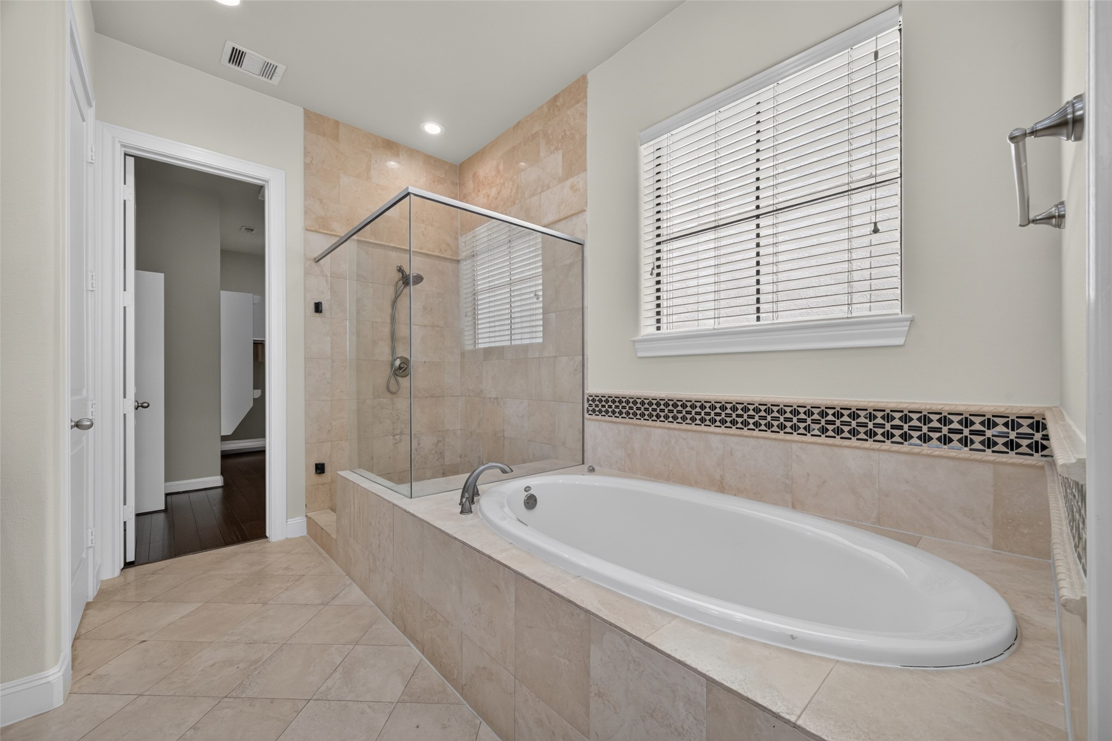 Elegant bathroom featuring a luxurious soaking tub and a spacious glass-enclosed shower, accented by stylish tile work and abundant natural light.