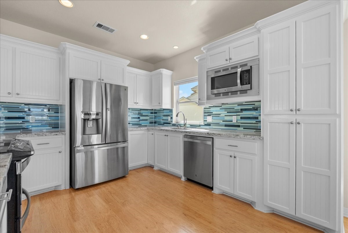 he kitchen impresses with designer backsplash, abundant cabinetry, stainless steel appliances, breakfast bar, and expansive granite countertops.