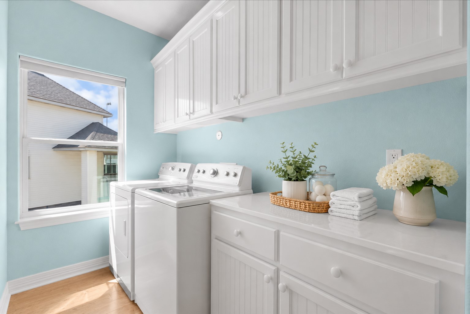 The laundry room offers generous counter space and an abundance of cabinetry for added storage and functionality.