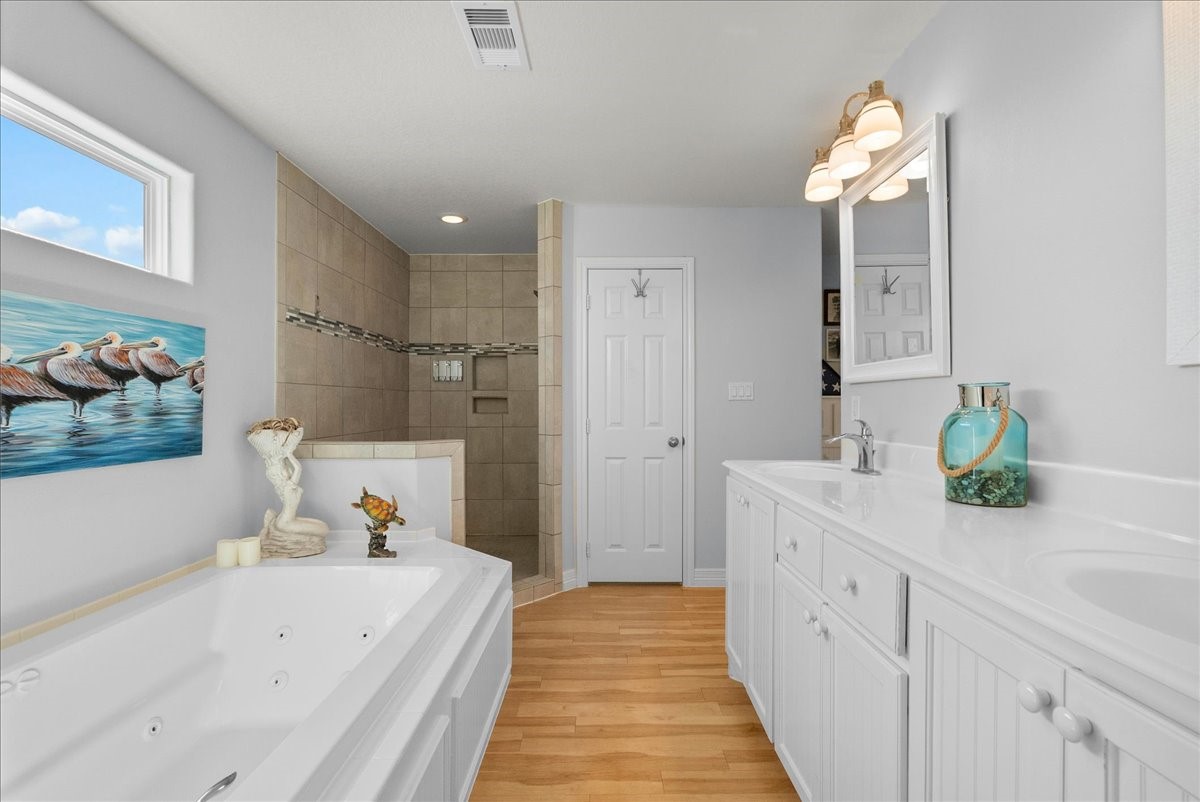 Spa-inspired en-suite with soaking tub, walk-in shower, dual sinks, and walk-in closet.