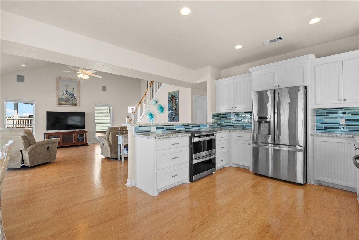 he kitchen impresses with designer backsplash, abundant cabinetry, stainless steel appliances, breakfast bar, and expansive granite countertops.