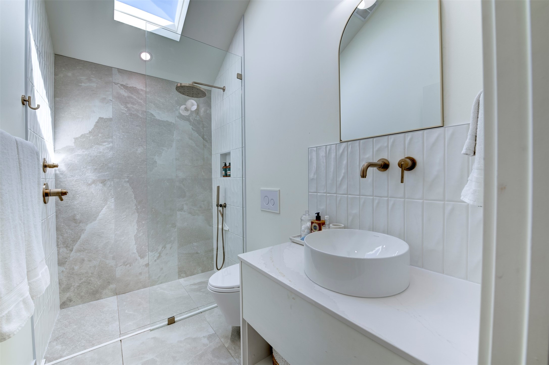 Back house bathroom with a skylight, a walk-in glass shower and a vessel sink.