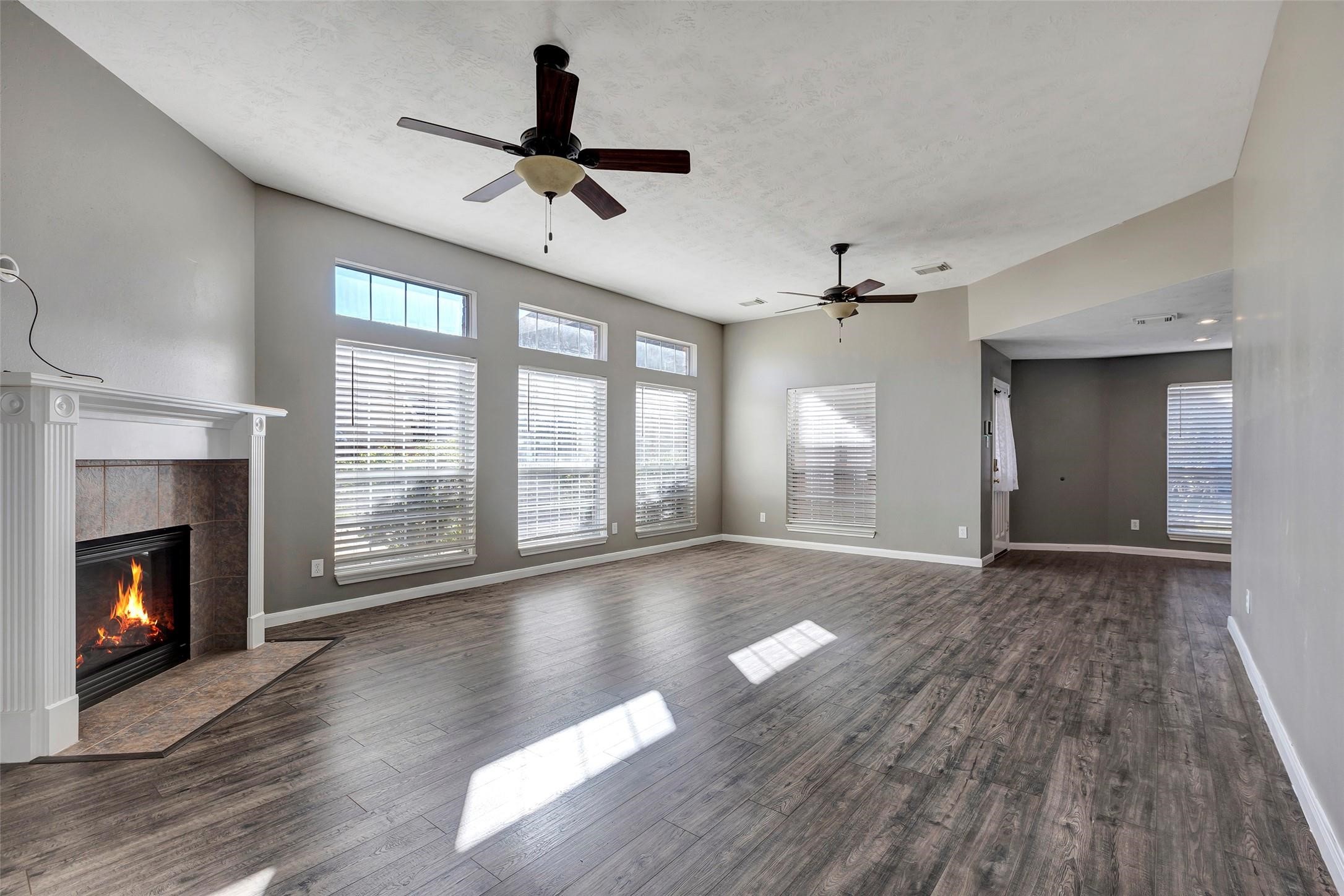 Living room features Twin ceiling Fans and a glowing fire place