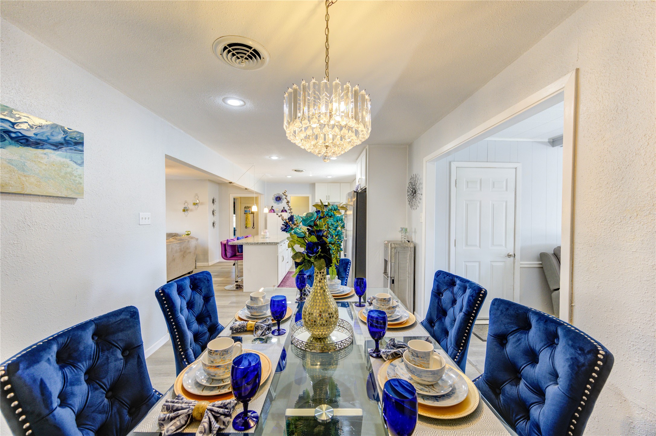 The dining room features a beautiful chandelier and opens into the bright, modern kitchen just off the den, creating a seamless flow for entertaining.