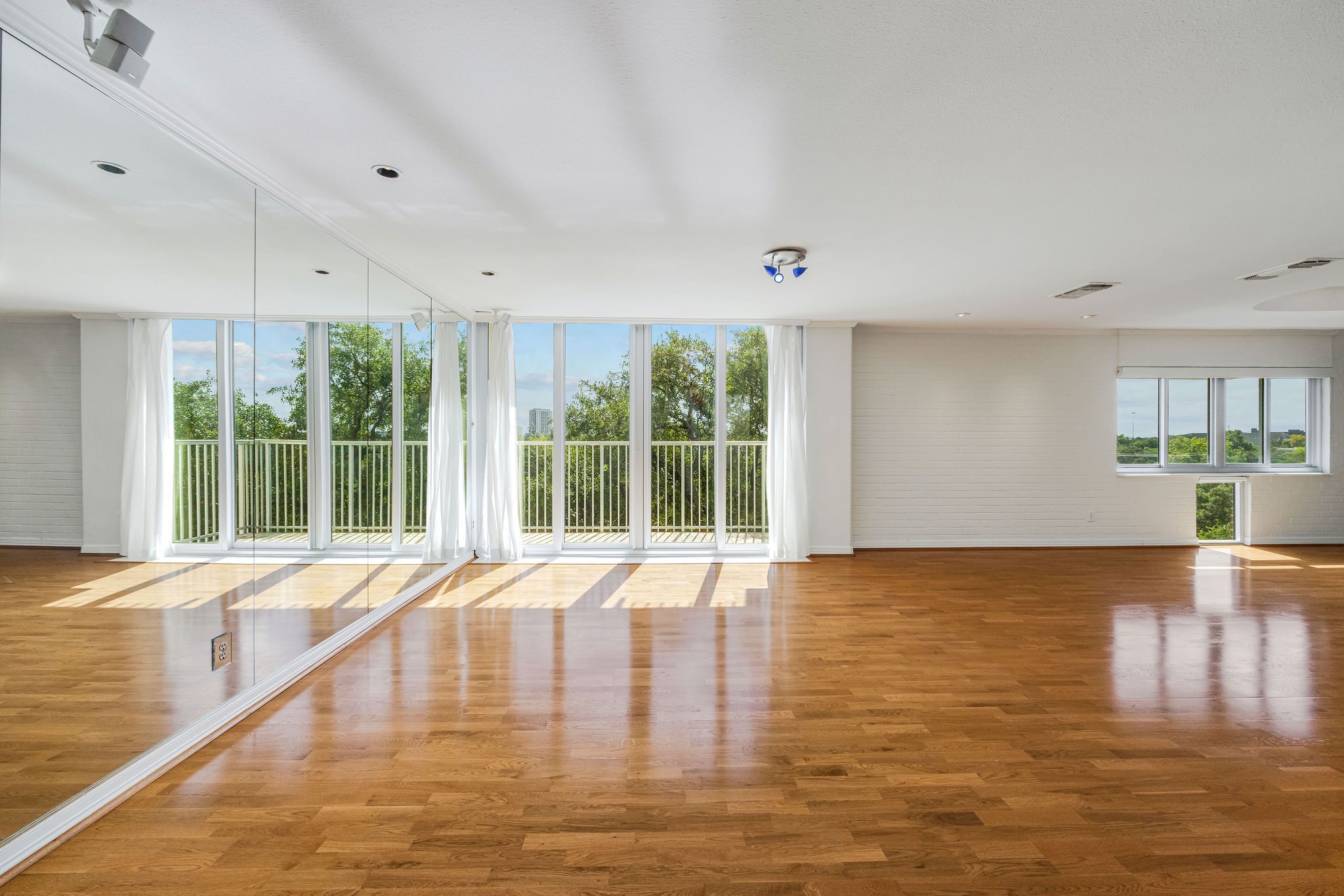 Spacious room with abundant natural light, featuring floor-to-ceiling windows and elegant hardwood floors.