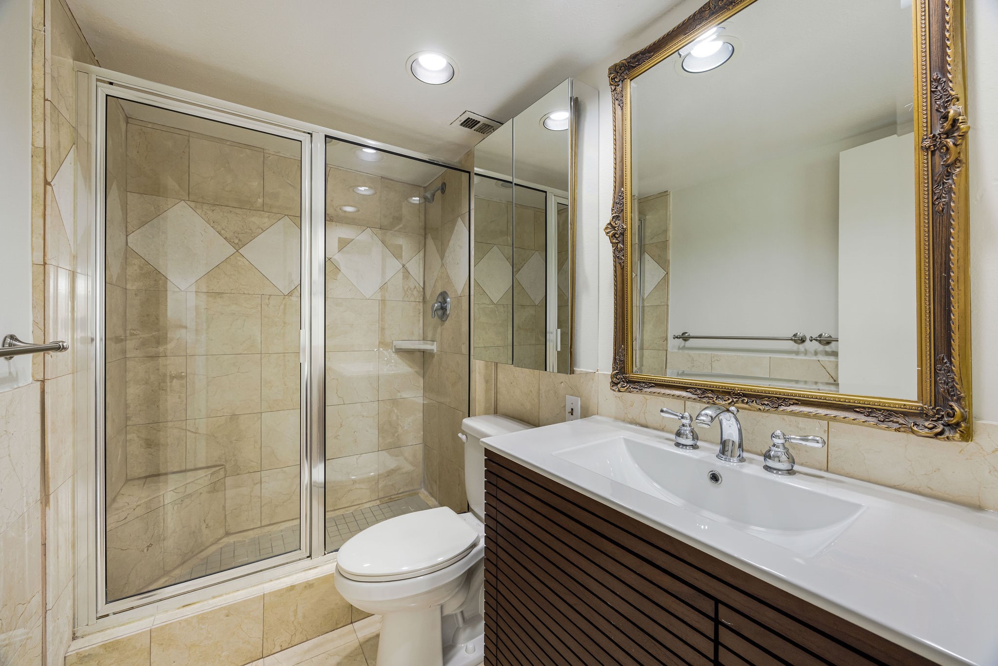 Elegant ensuite bathroom featuring a spacious glass-enclosed shower with stylish tile accents, a sleek modern vanity, and a large ornate mirror for a touch of luxury.