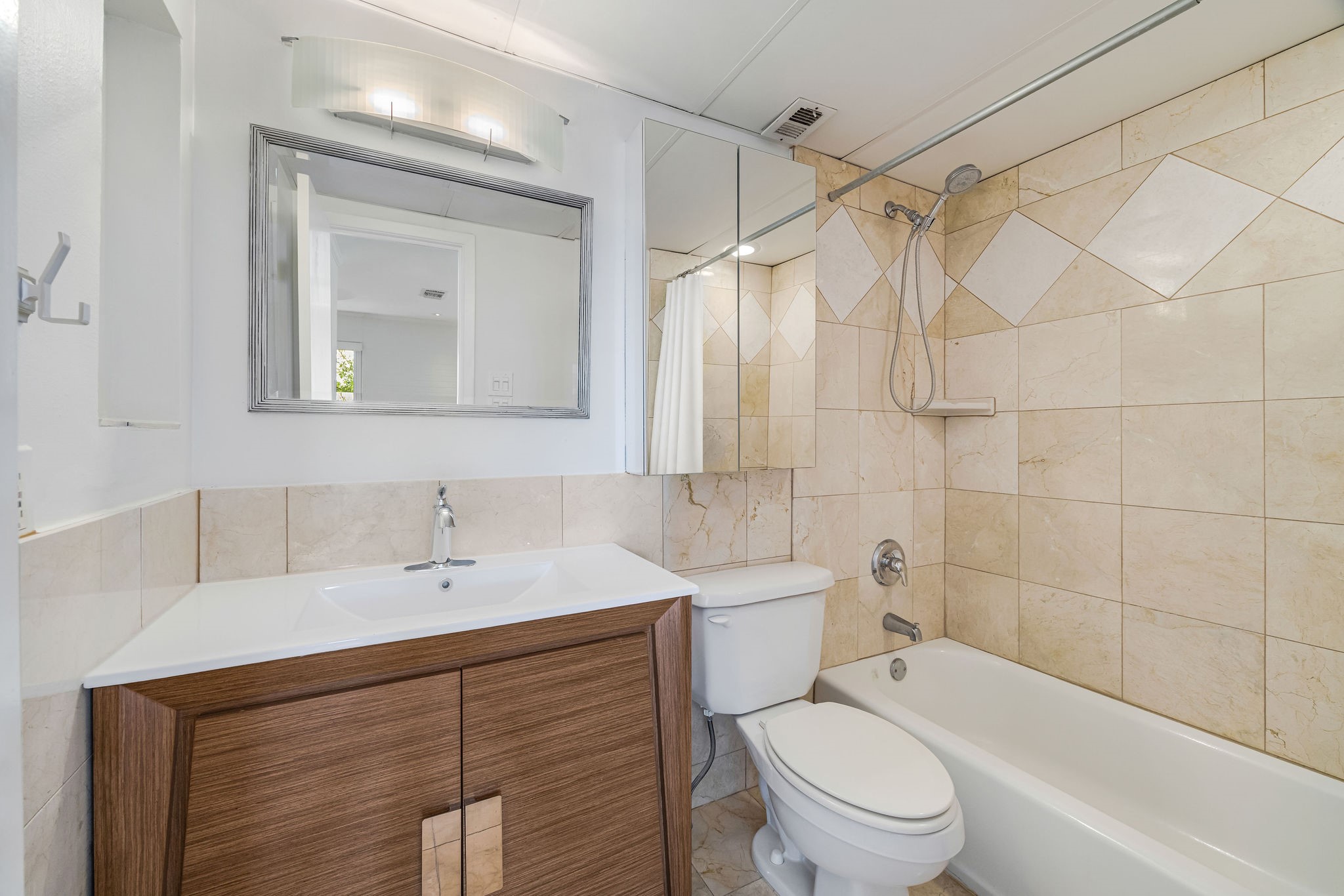 Modern bathroom featuring sleek tile work, a stylish vanity with a large mirror, and a combined shower and bathtub for a contemporary feel.