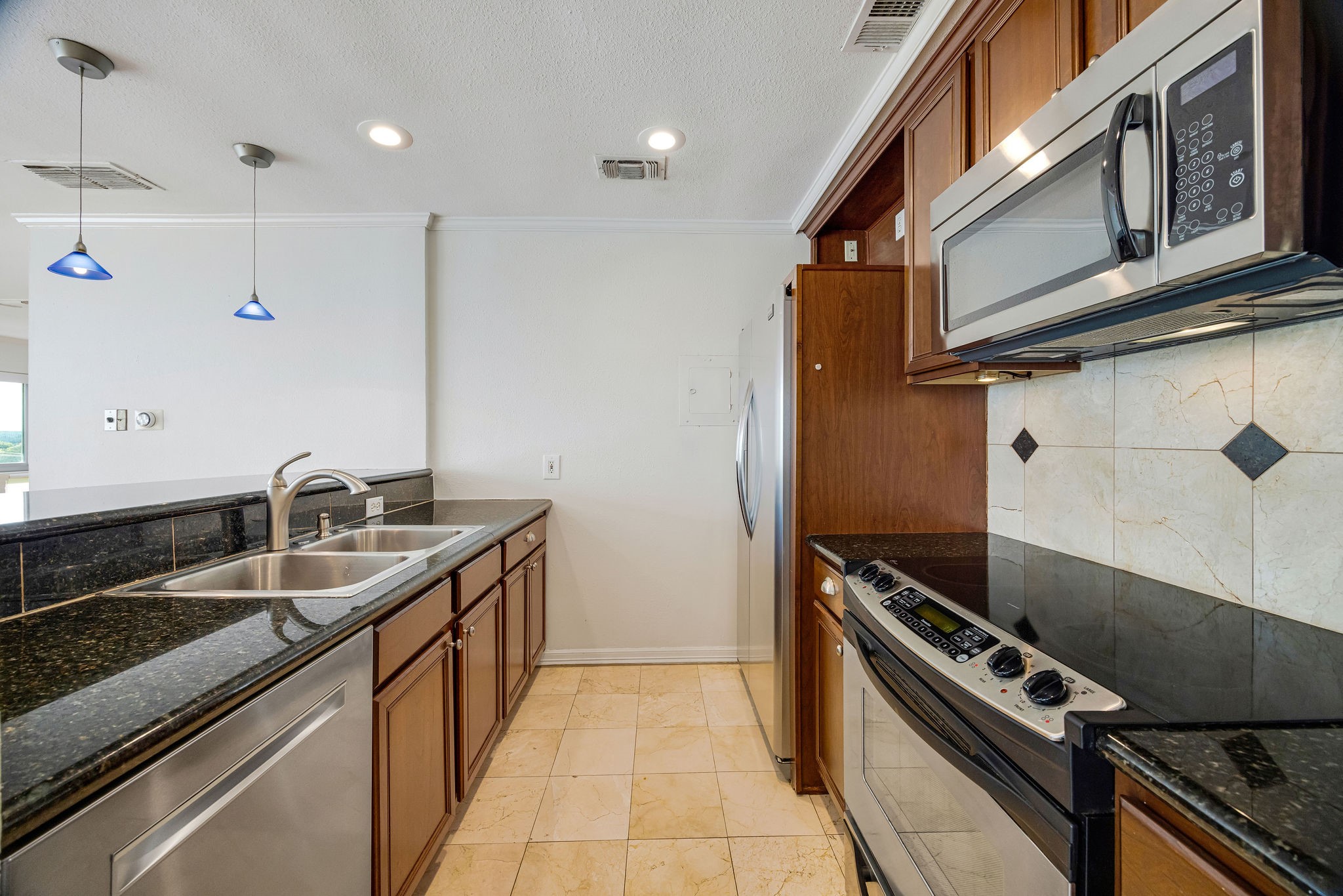 Modern kitchen with sleek stainless steel appliances, granite countertops, and elegant tile backsplash, offering a perfect blend of style and functionality.