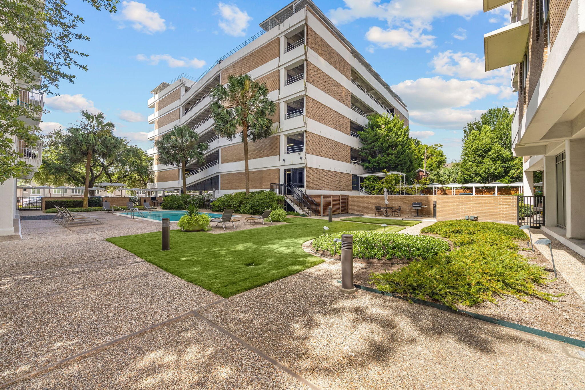 Beautifully landscaped courtyard featuring a sparkling pool, lush greenery, and ample lounging space.