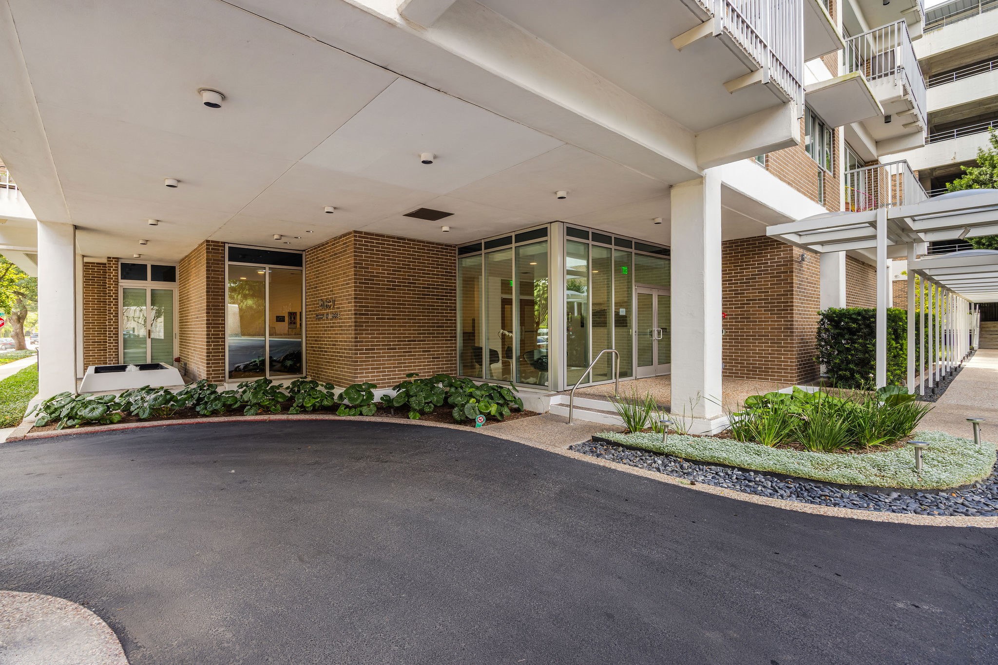 The building entrance has a covered driveway, sleek glass doors, and well-maintained landscaping, offering both style and convenience.