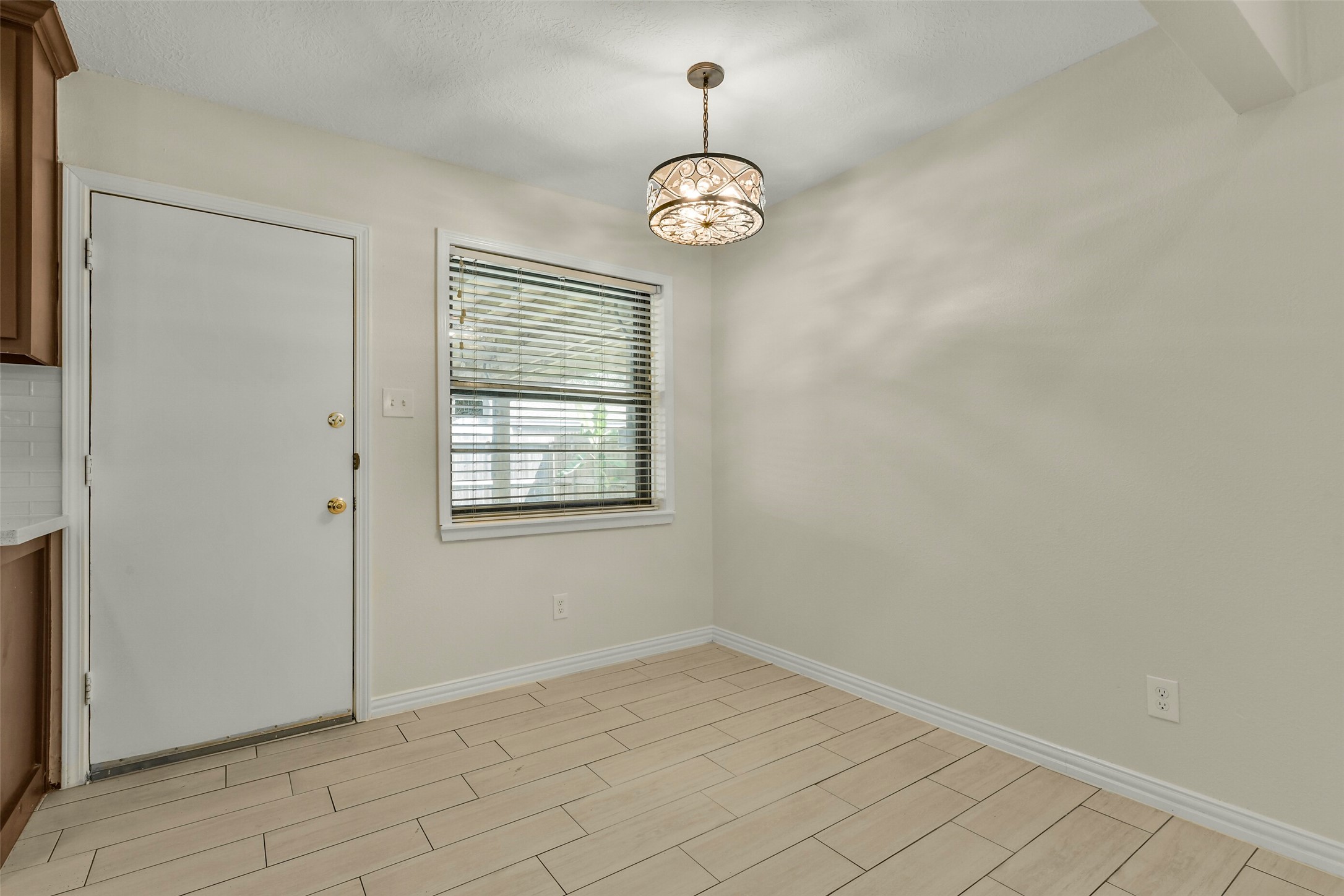 Dining nook features elegant tile flooring, a modern light fixture, and ample natural light from a large window, perfect for cozy meals.