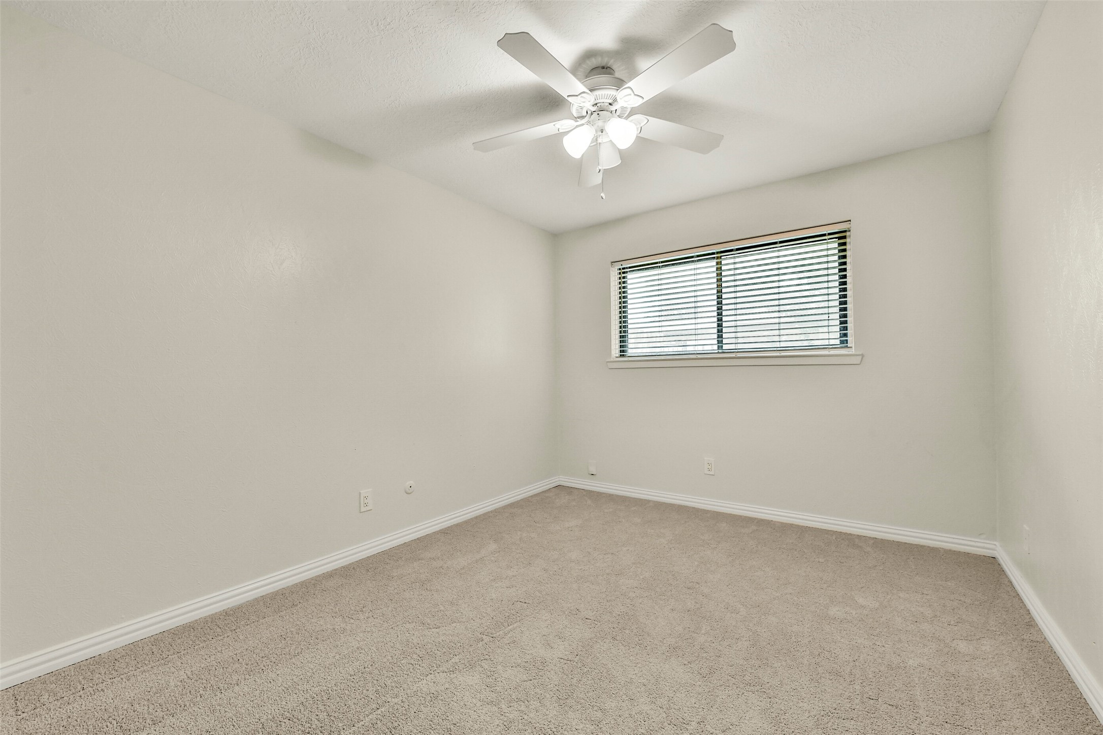Bedroom with plush carpeting, a ceiling fan, and a large window offering ample natural light.