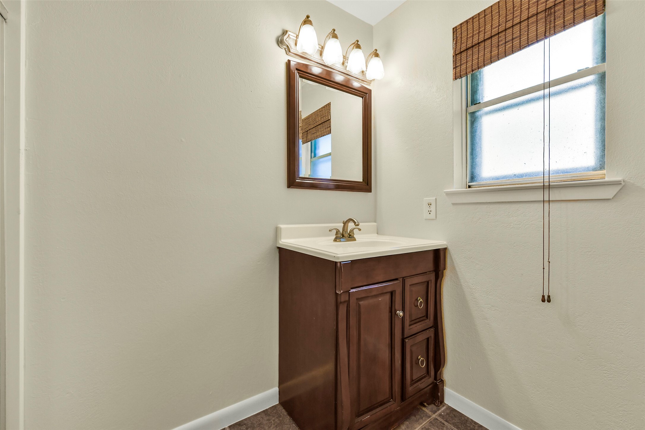 Bathroom features a classic dark wood vanity with ample storage, complemented by a sleek mirror and elegant lighting.
