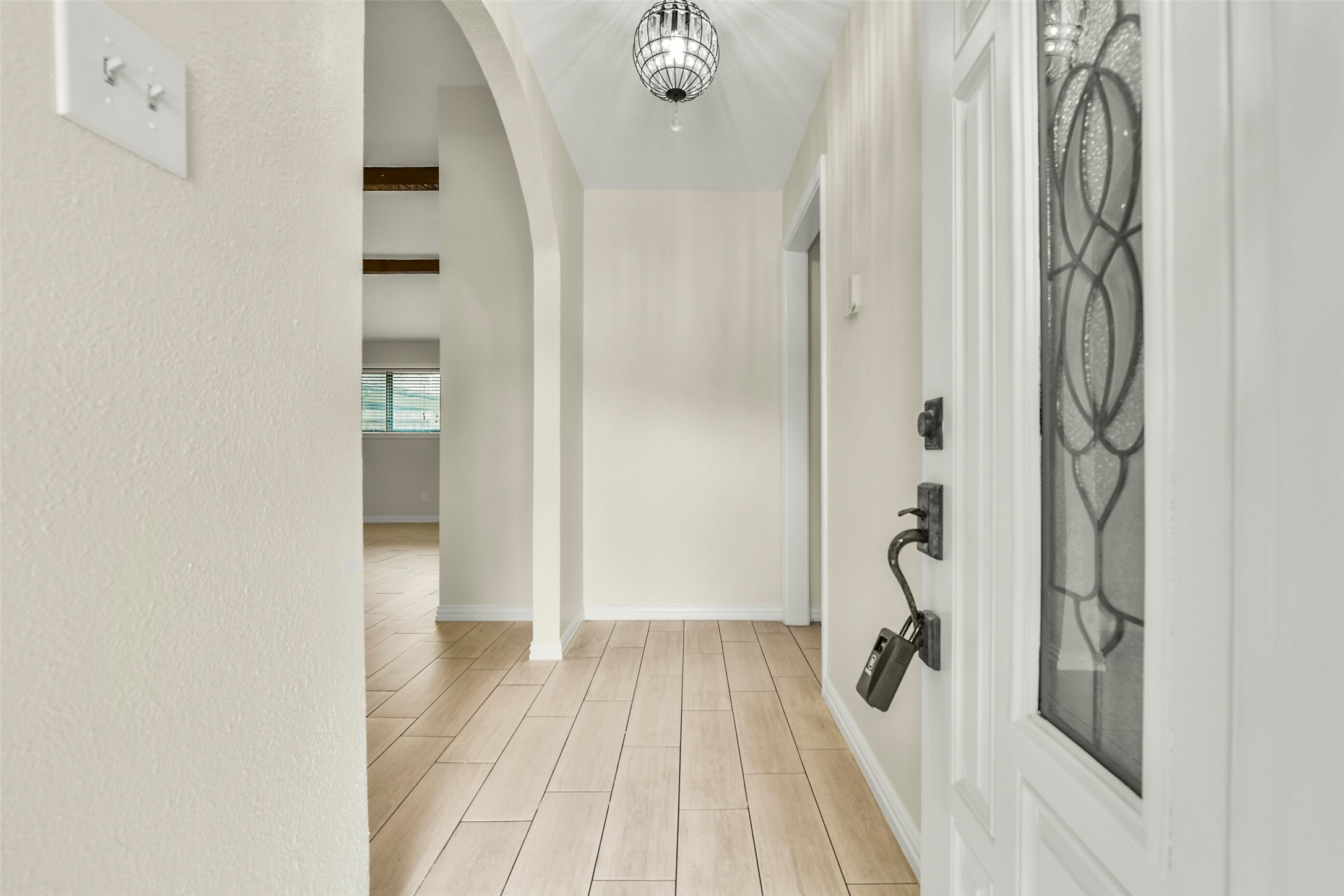 Inviting entryway with elegant tile flooring, arched doorway, and a stylish hanging light fixture, leading to a bright and open living area. Inviting entryway with elegant tile flooring, arched doorway, and a stylish hanging light fixture, leading to a bright and open living area.