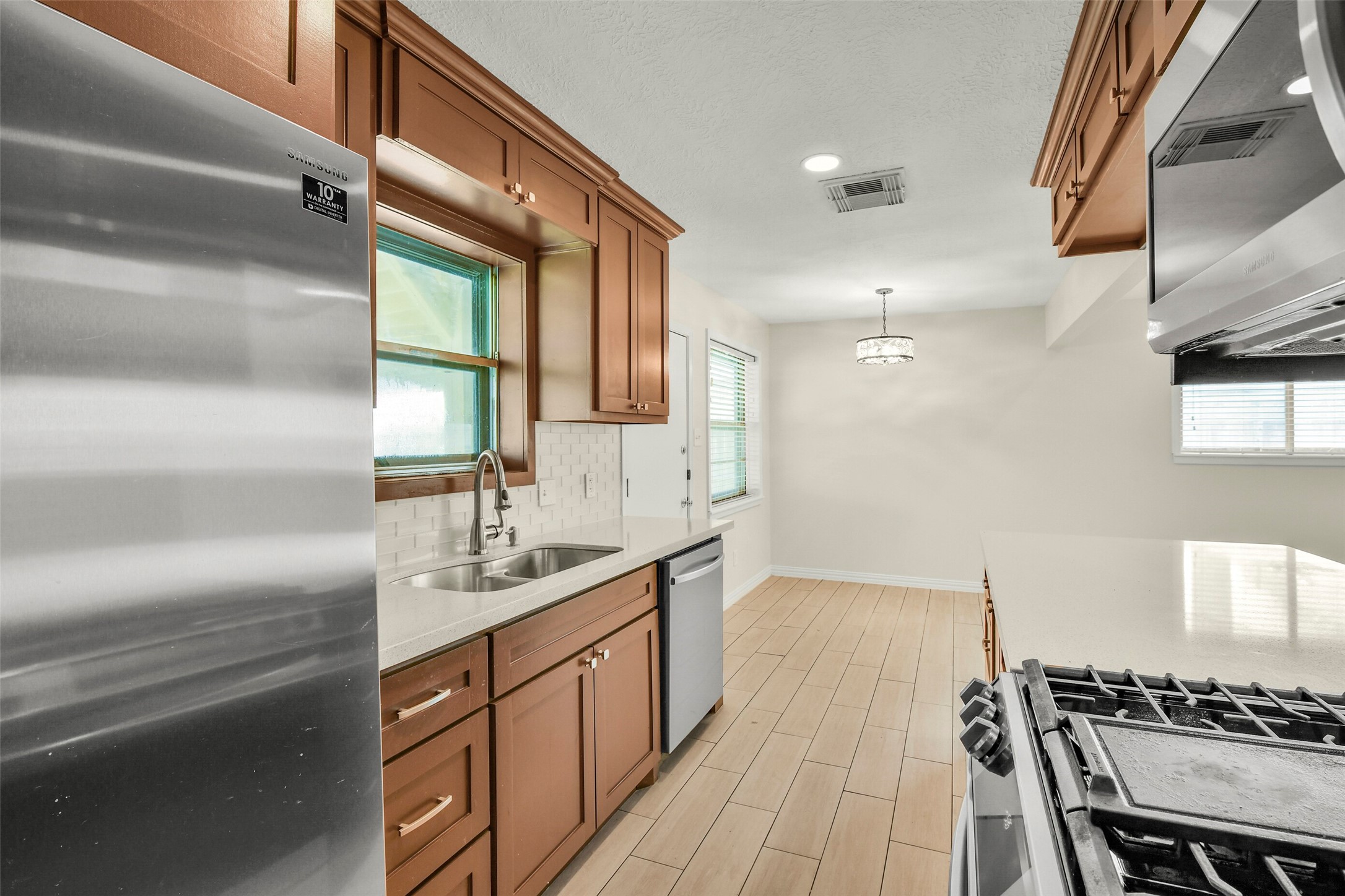 Modern kitchen with sleek stainless steel appliances, warm wood cabinetry, and a spacious layout perfect for cooking and dining.
