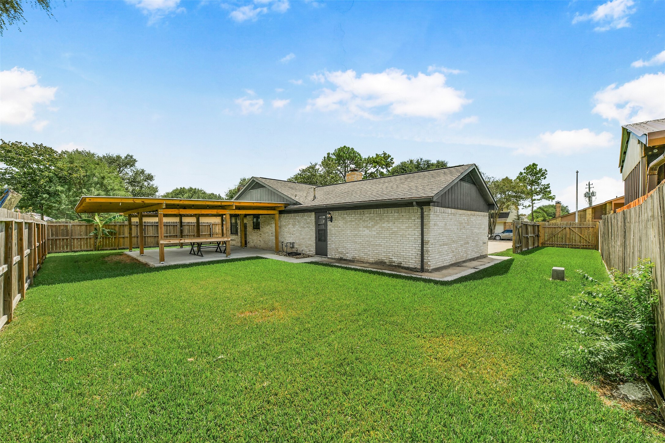 Spacious backyard featuring a covered patio area perfect for outdoor dining and entertainment, surrounded by a privacy fence.