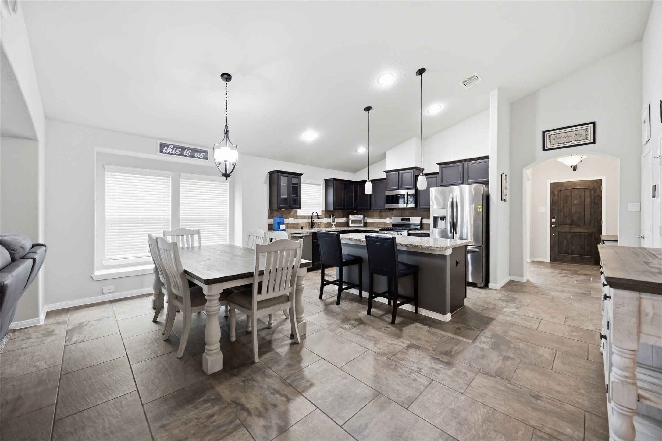Spacious open-concept kitchen and dining area featuring modern appliances, elegant dark cabinetry, and a large island with bar seating, perfect for entertaining.