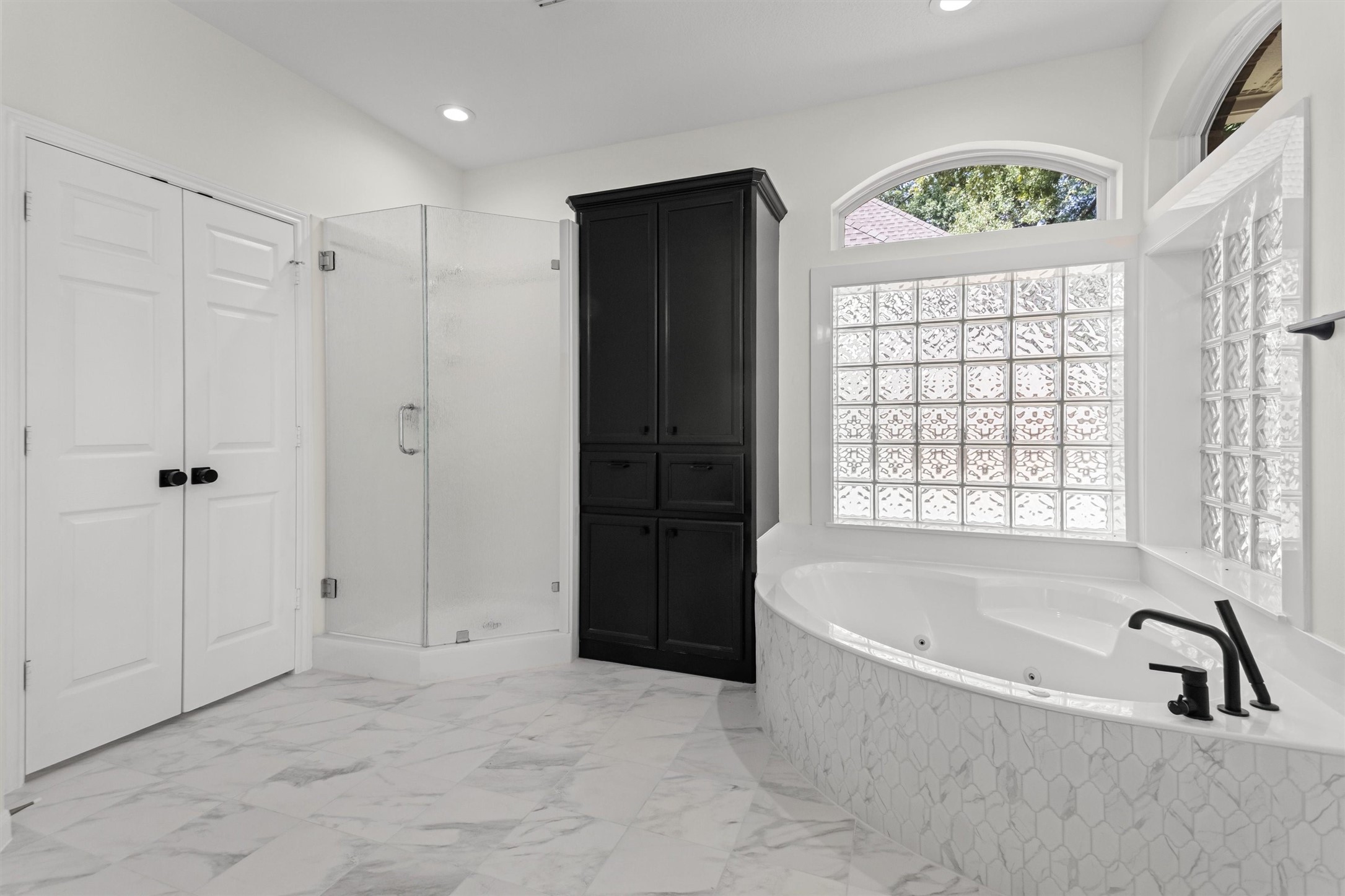 The primary suite flows into a spa-inspired bathroom featuring a corner jetted tub, a separate shower, a spacious walk-in closet, and a convenient linen tower cabinet.