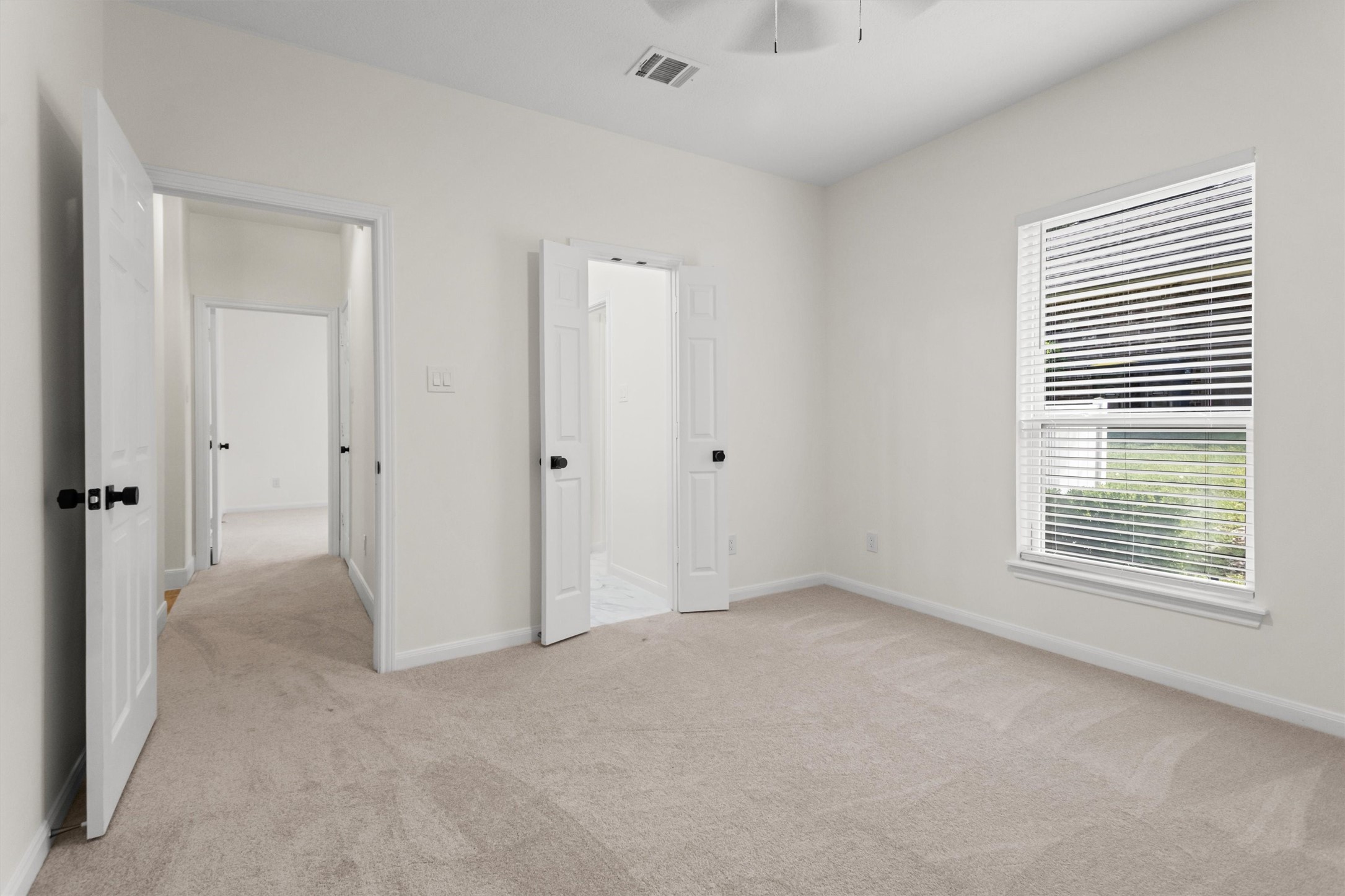 The second secondary bedroom is generously sized and features a convenient Hollywood bath. This view highlights the access points to both the private bathroom and the main hallway.
