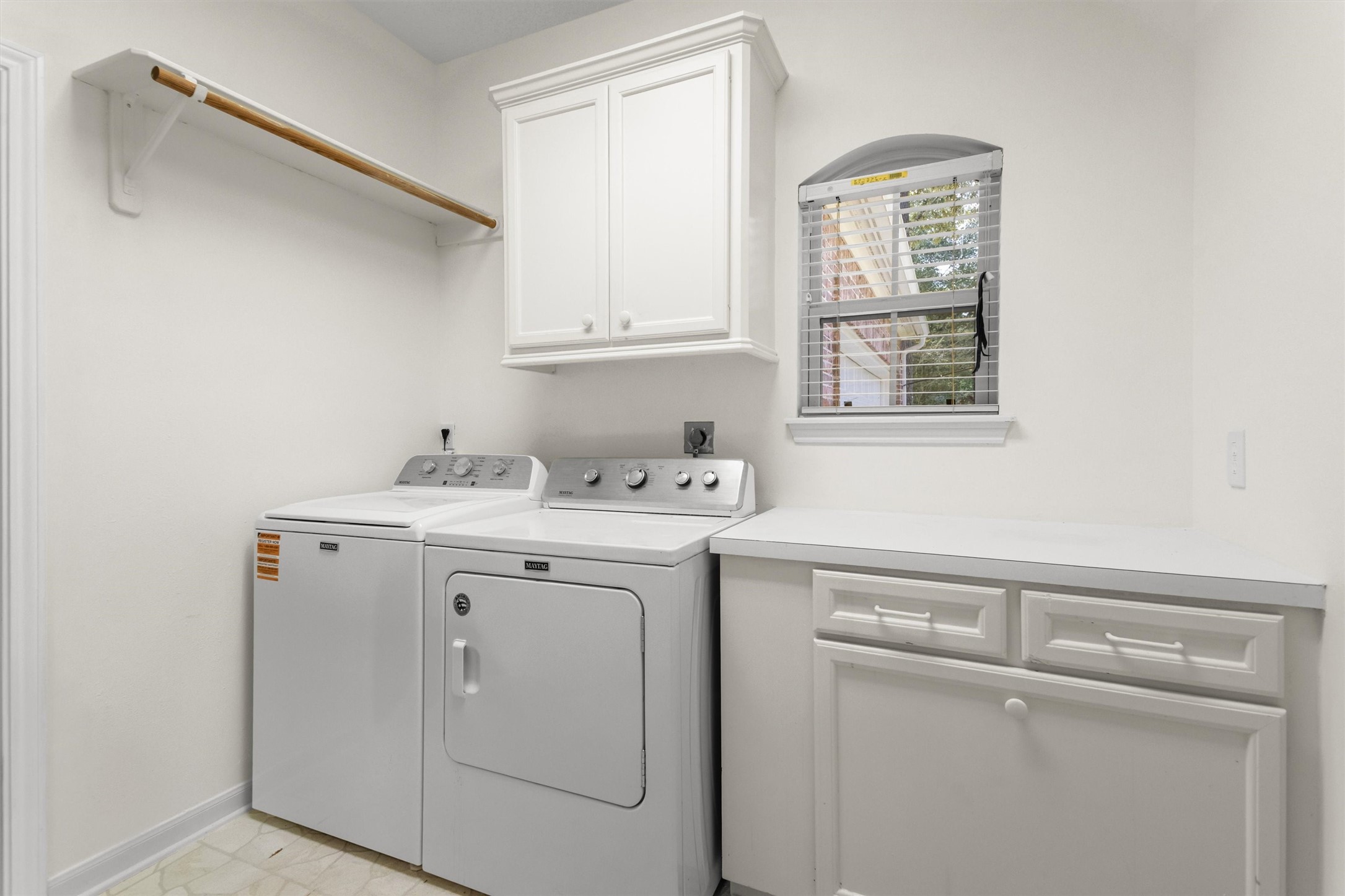 Another view of the laundry room featuring the folding workspace and a window that provides natural light. Washer and dryer are included.