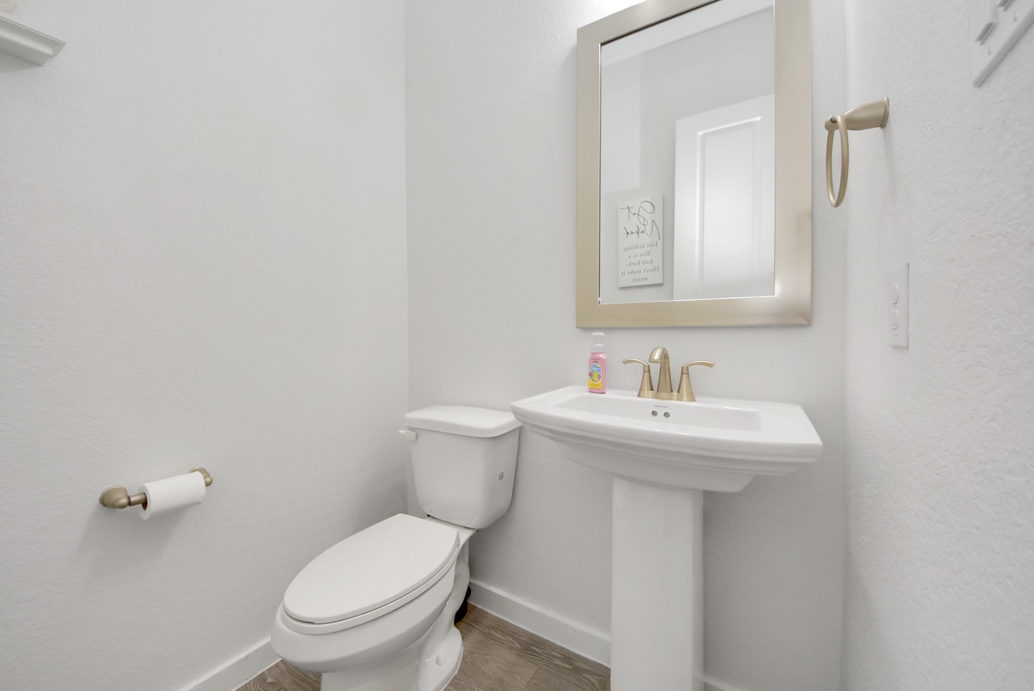 Convenient half bathroom featuring a pedestal sink and neutral finishes.