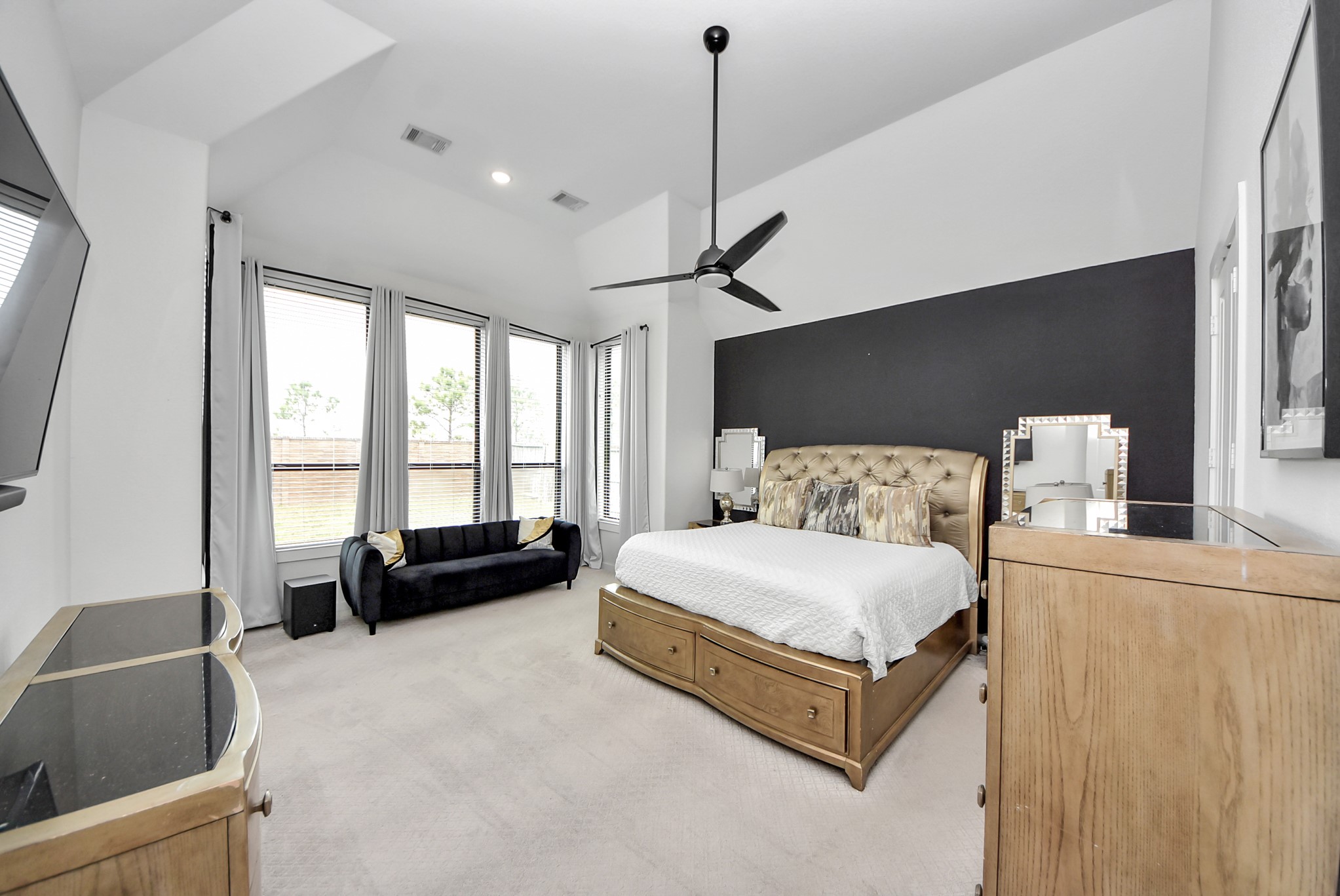 Spacious primary bedroom featuring a stylish accent wall and large windows.