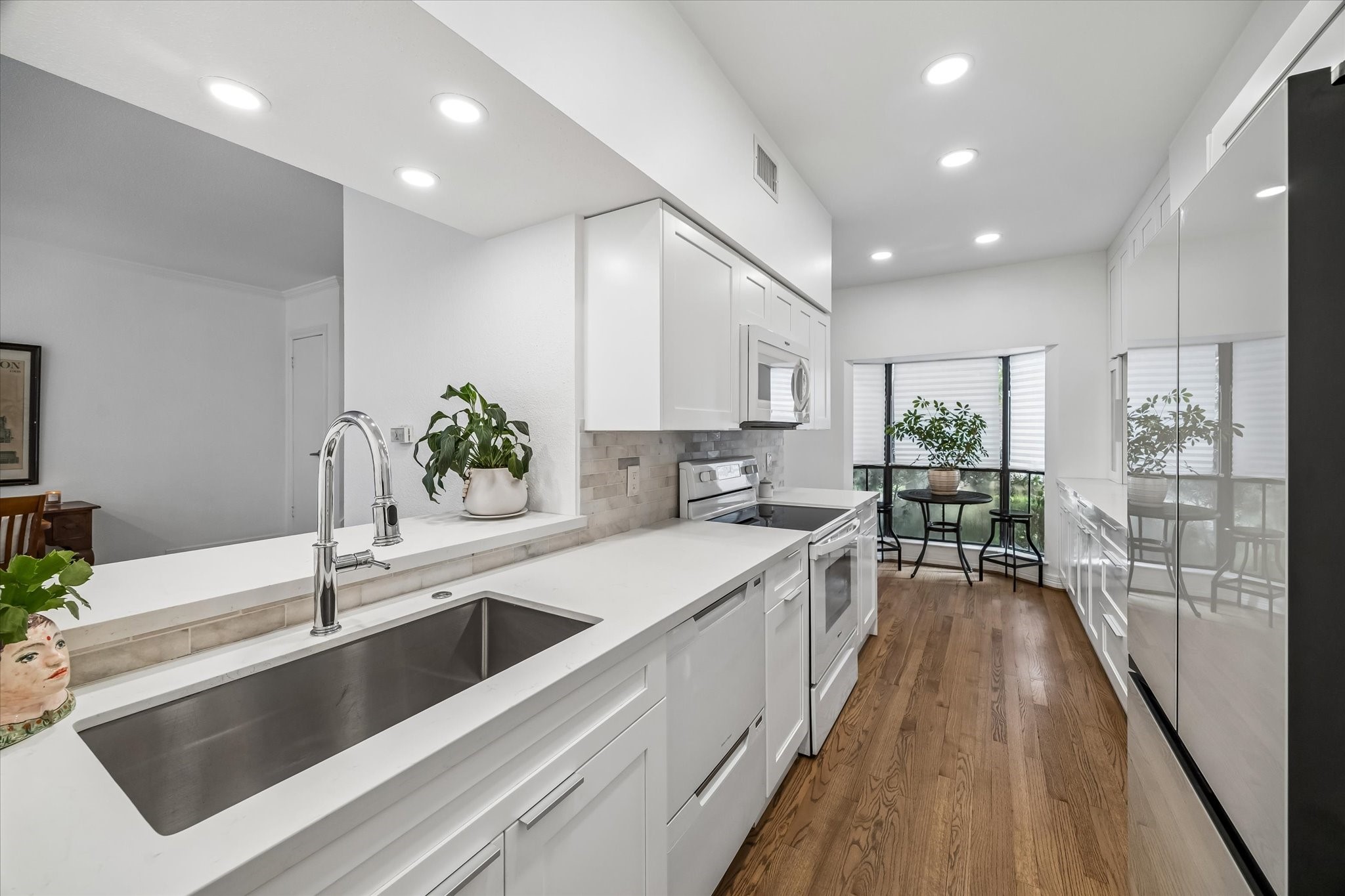 Bright and modern kitchen with sleek white cabinetry, updated appliances, updated sink, faucet, and disposal. New pantry.