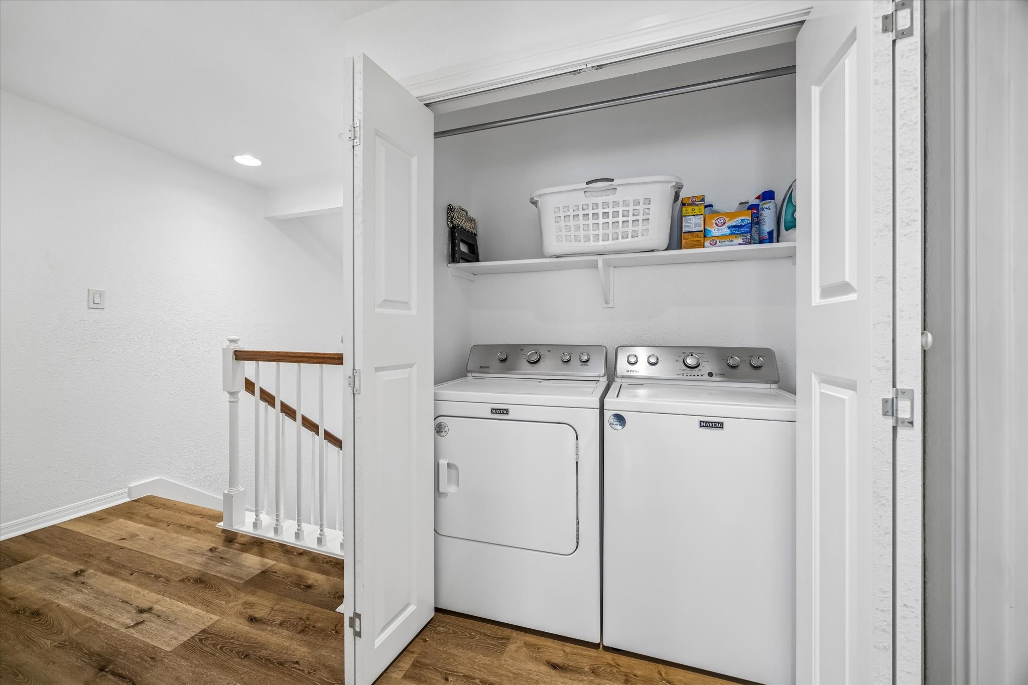 Convenient laundry nook with a Maytag washer and dryer (2022) neatly tucked behind bi-fold doors, featuring a shelf for storage.