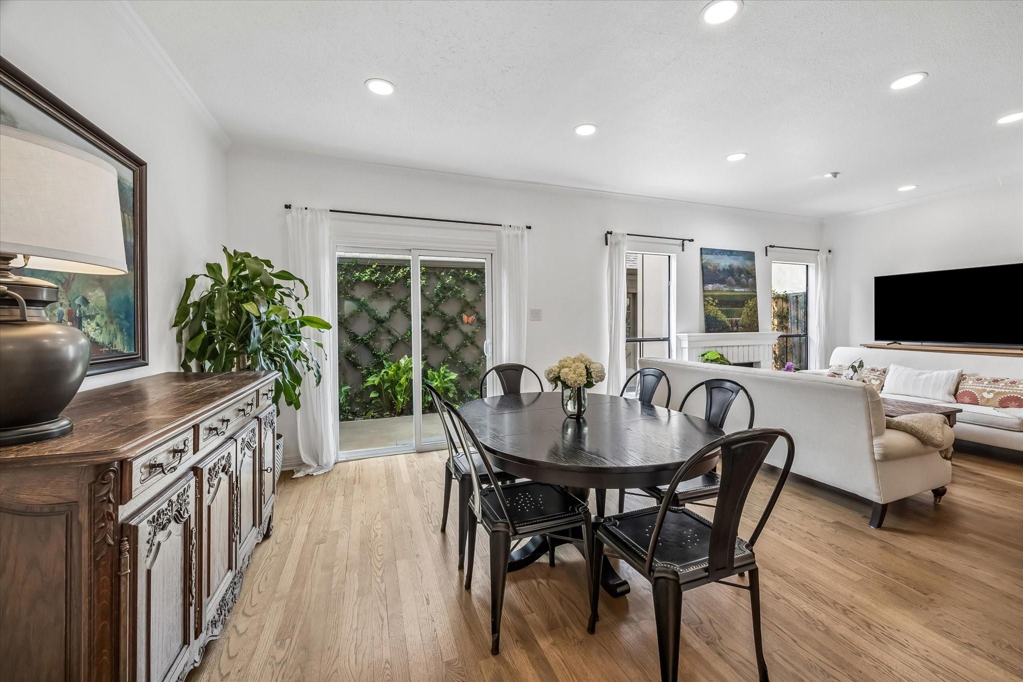 Bright and inviting open-plan living area with hardwood floors, featuring new sliding glass doors. New crown, molding, and baseboards throughout.