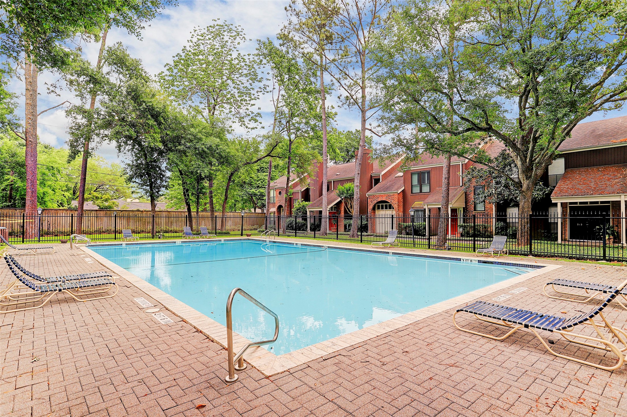 Enjoy a refreshing retreat in this inviting community pool, surrounded by lush greenery and charming townhouses, perfect for relaxation and leisure.