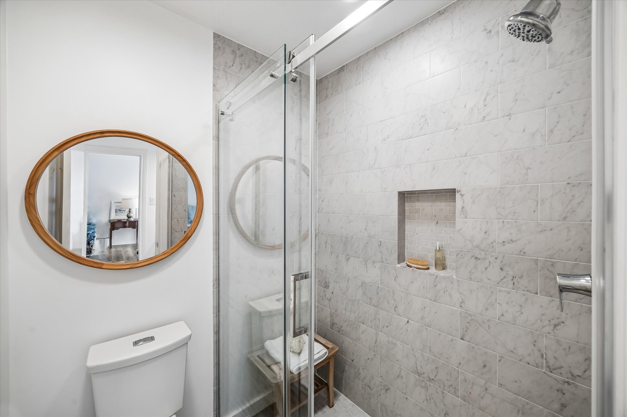 Elegant bathroom featuring a spacious marble-tiled shower with a glass door and built-in niche.