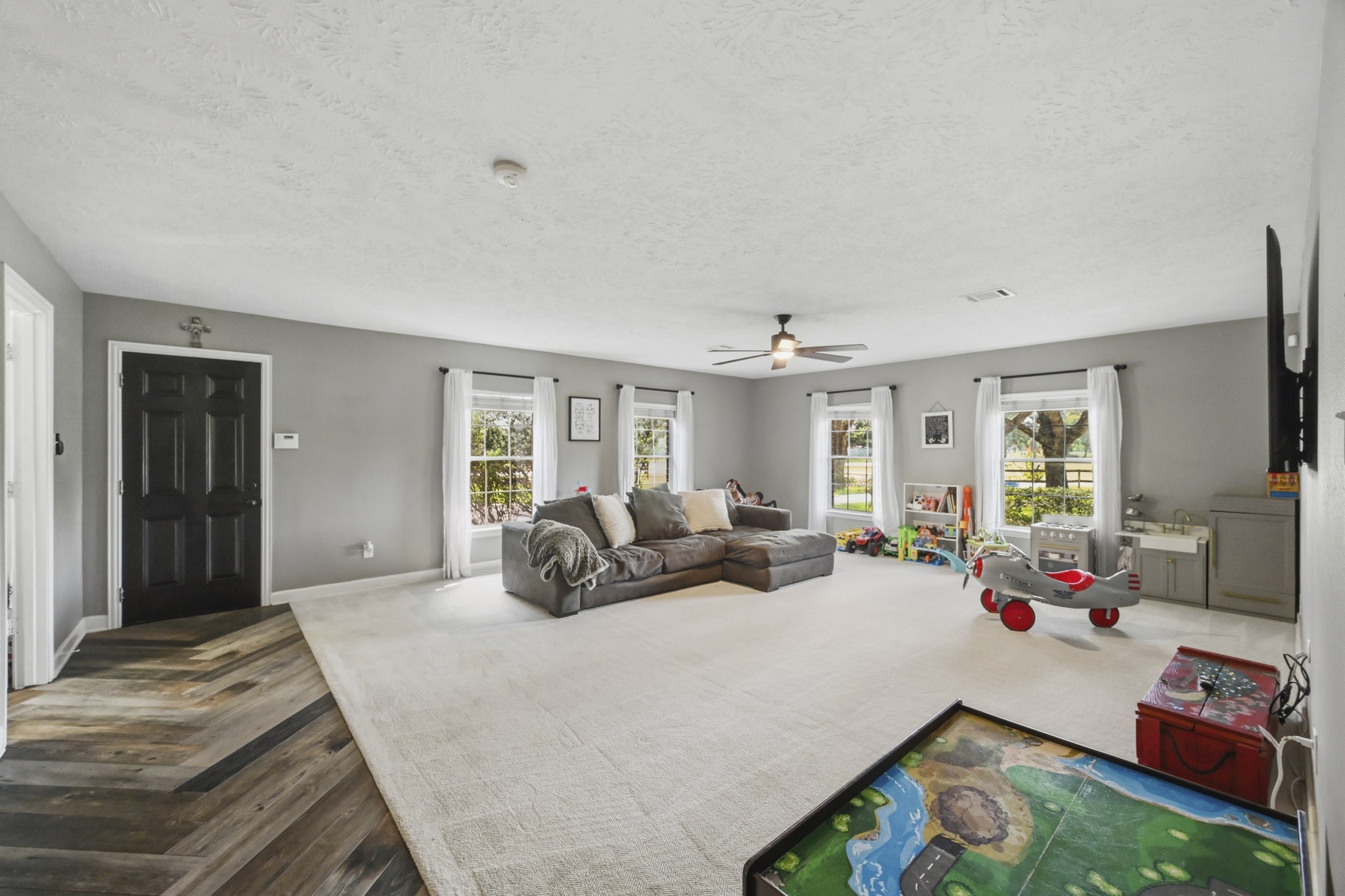 Spacious game room with access to the garage and views of the wooded front yard.