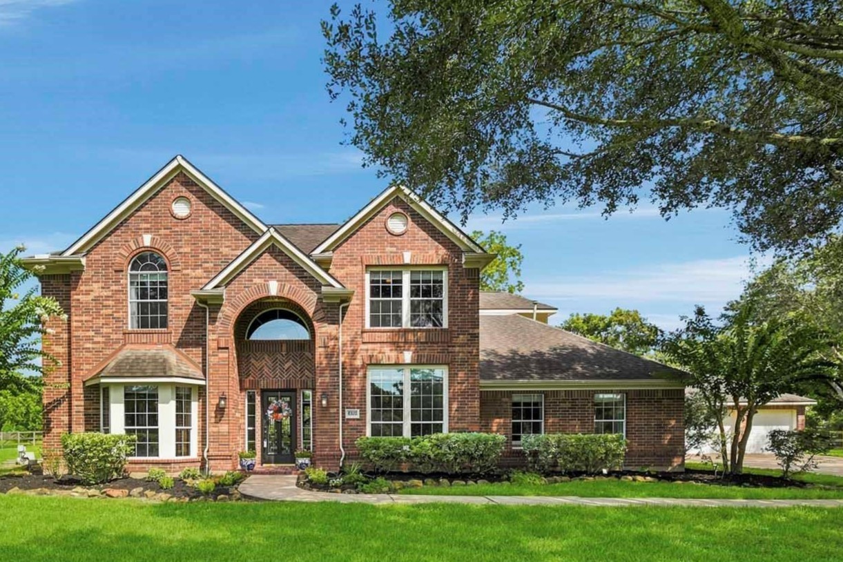 Stunning front elevation nestled on 1.68 wooded acres with expansive outdoor space and mature trees.