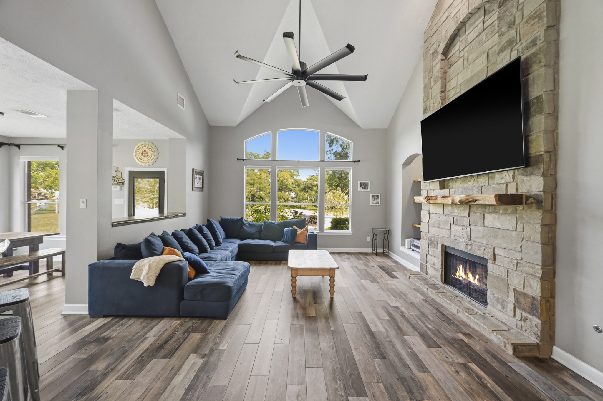 Inviting family room with soaring ceilings, a floor-to-ceiling stone fireplace, and breathtaking backyard views.