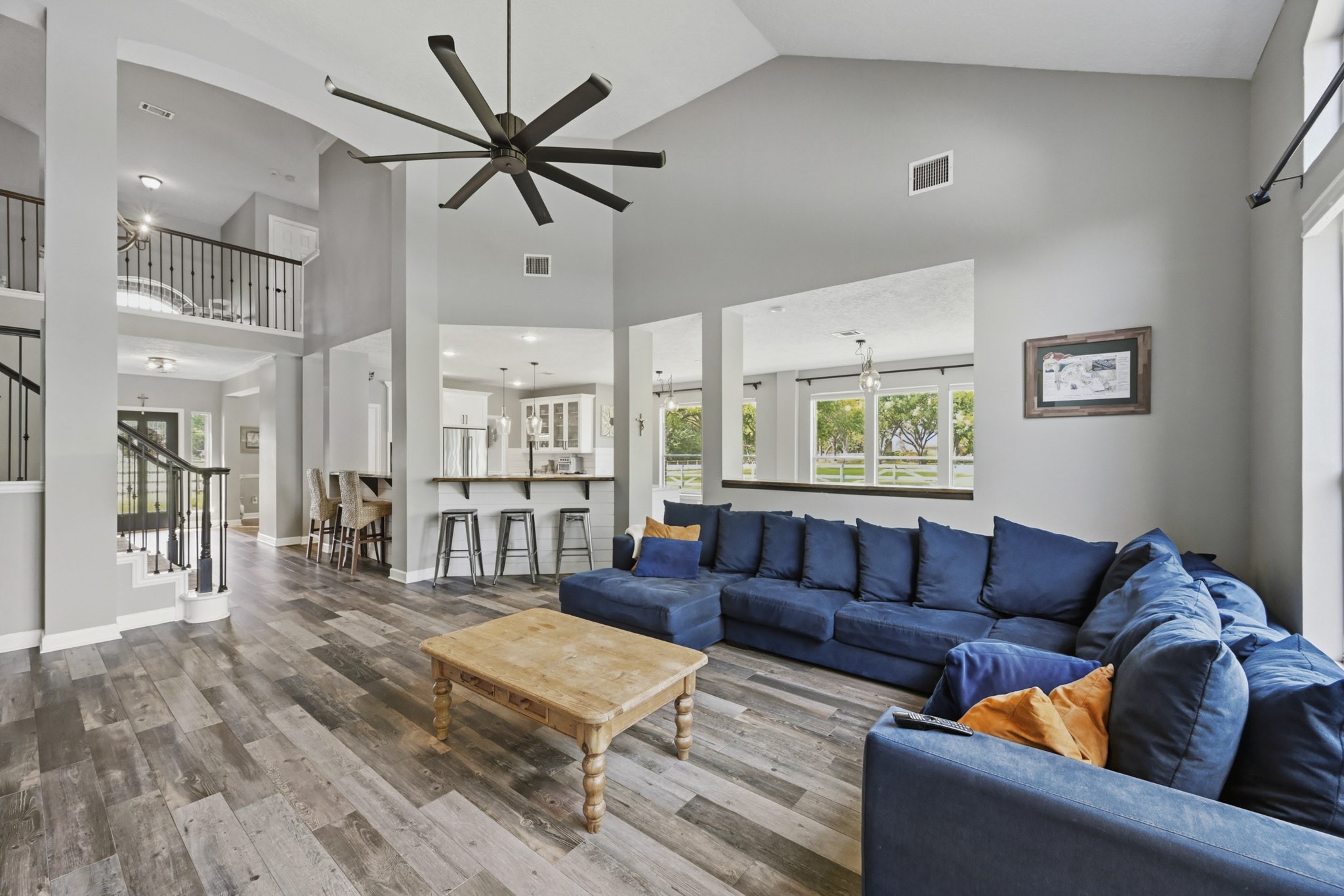 Open-concept living area featuring the kitchen, breakfast bar, butlers pantry, grand staircase, and beautiful flooring.