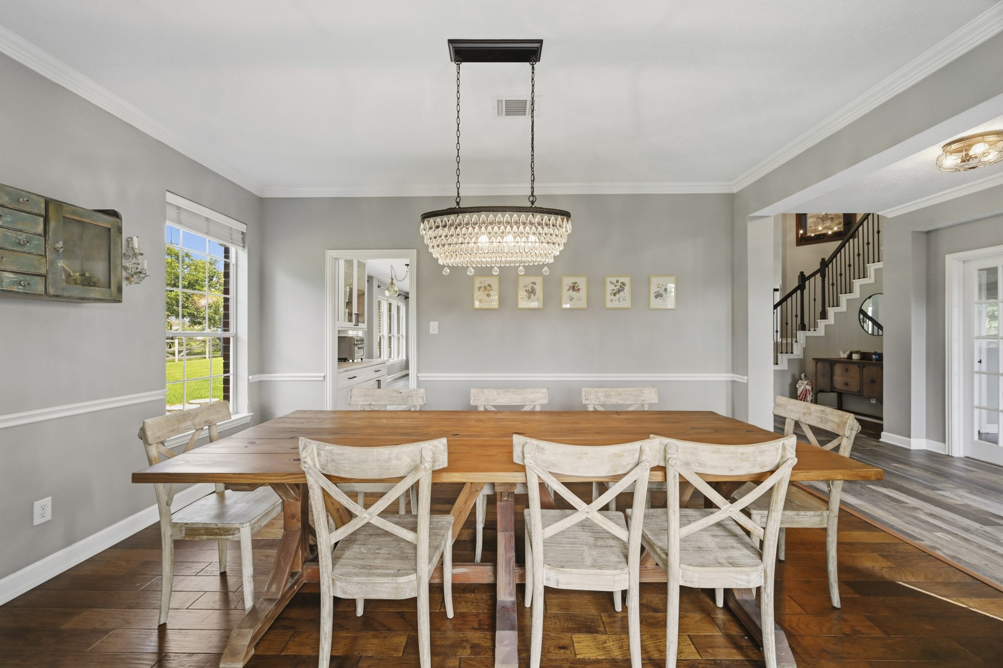 Formal dining room featuring crown molding, beautiful flooring, abundant natural light, and a statement chandelier.