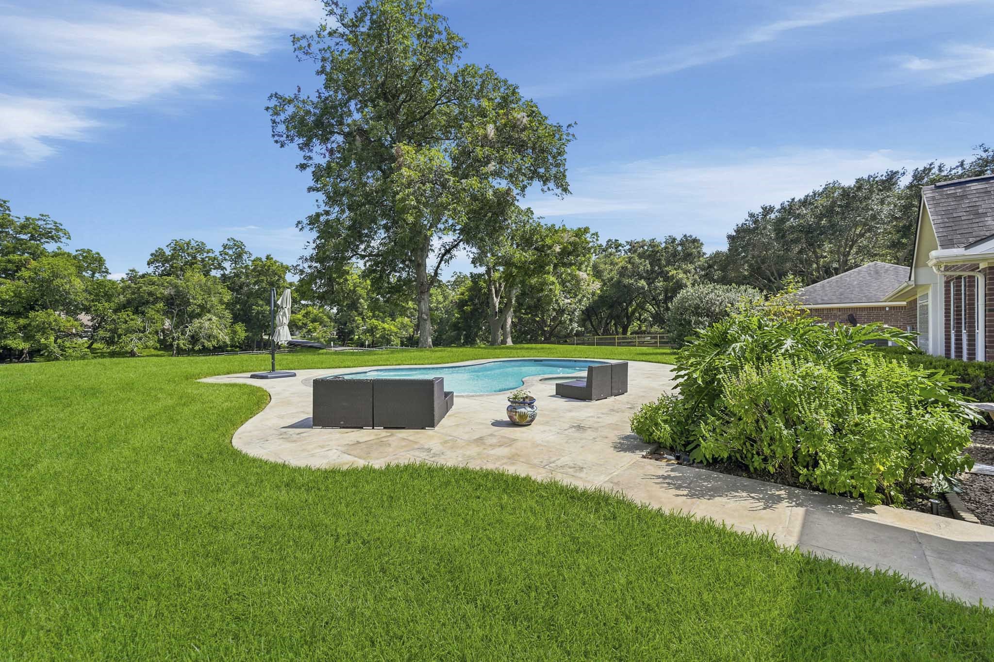 Resort-style heated pool and spa overlooking the serene, tree-lined backyard.