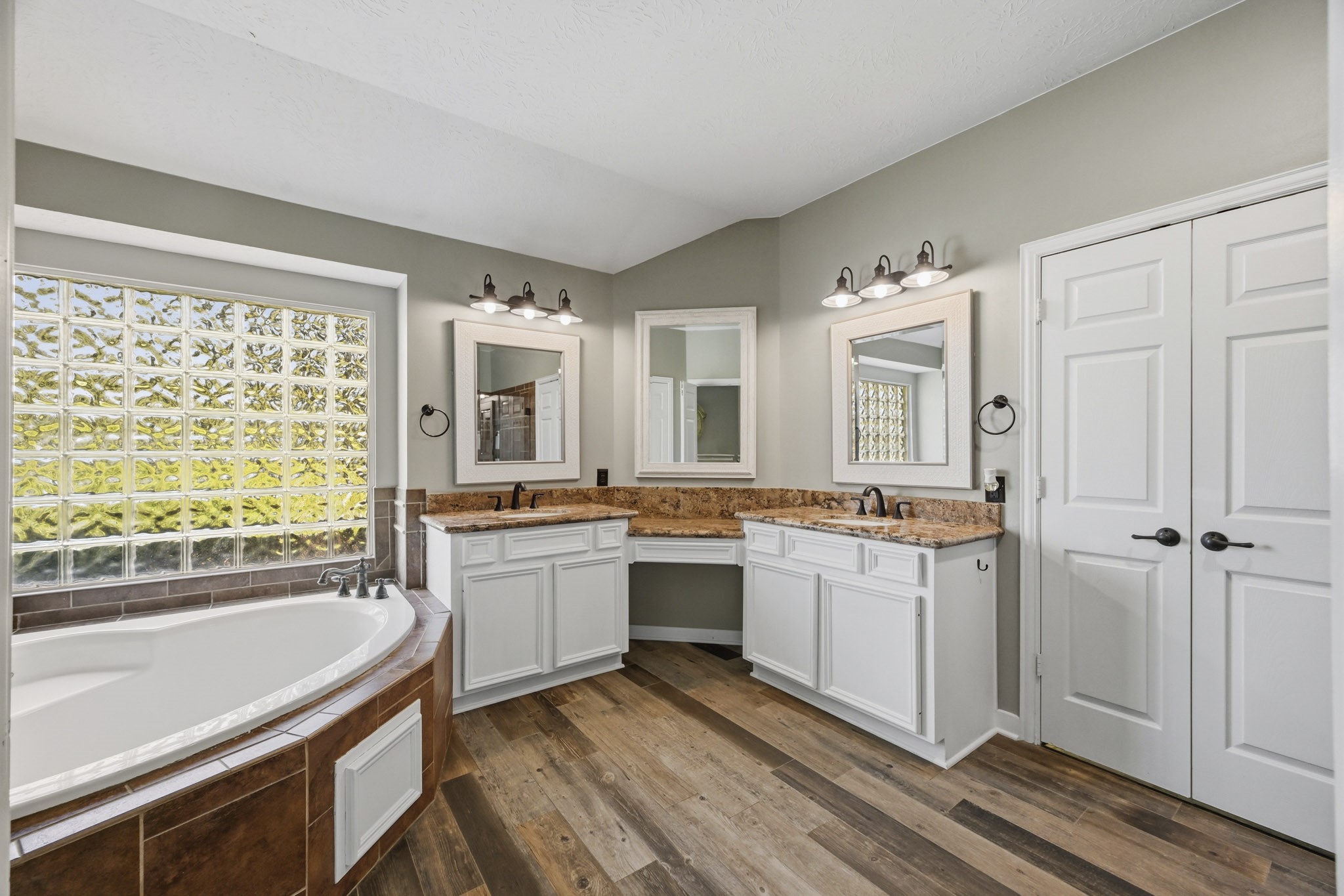 Primary bath featuring an oversized soaking tub, dual vanities, granite countertops, and a dedicated vanity area.