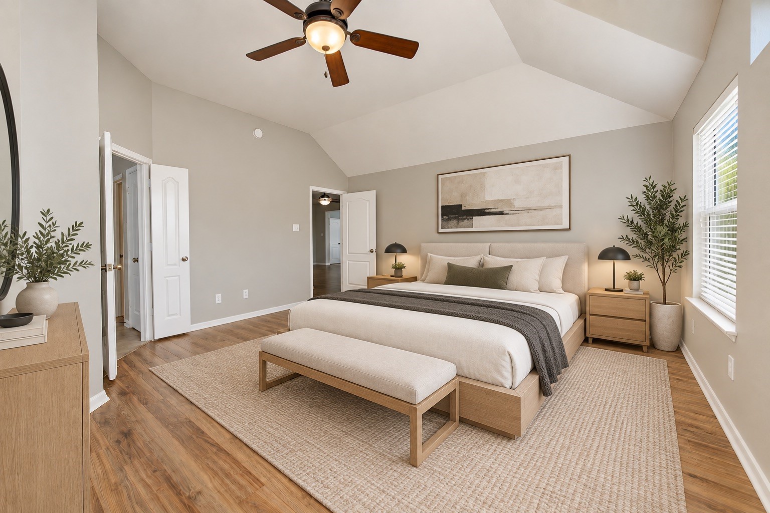 Spacious and inviting primary suite featuring beautiful vaulted ceilings, warm wood flooring, a ceiling fan, and plenty of natural light. Virtually staged to help visualize the rooms potential.
