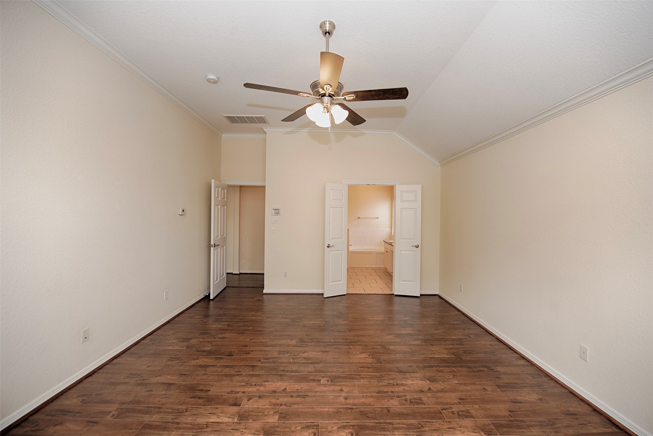 A view of the primary suite to the en suite bathroom. This room also features the gorgeous wood laminated floors.