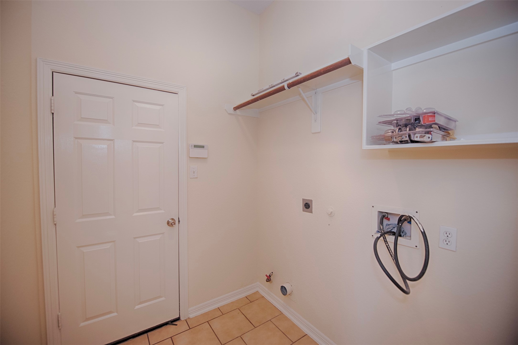 Utility room with door to the garage. There is built in shelving for your laundry essentials and hanging rod for hanging your clothes as you remove from the dryer.