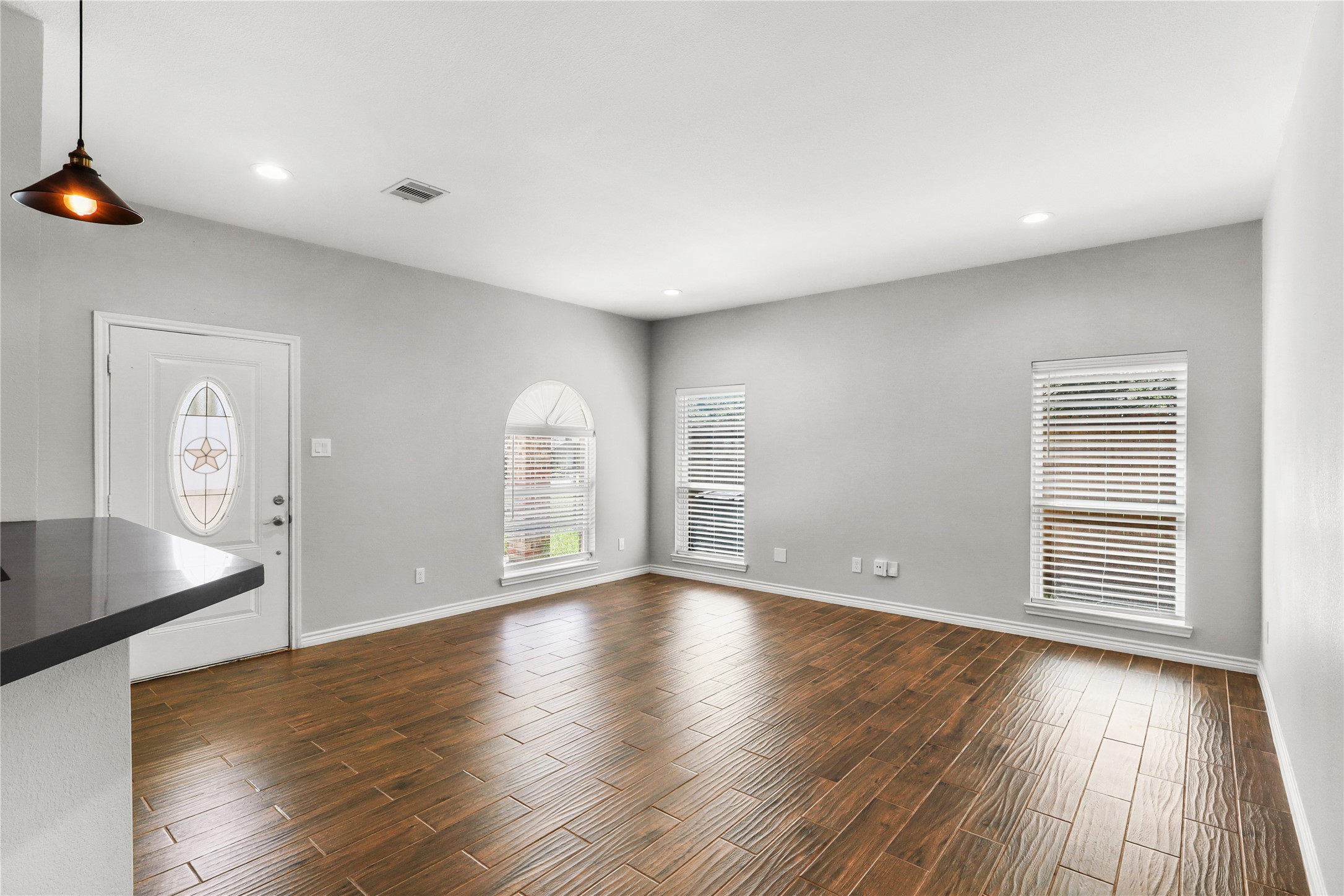View of the living room and a front door. Look at all the windows. Two inch white blinds already added to every window.