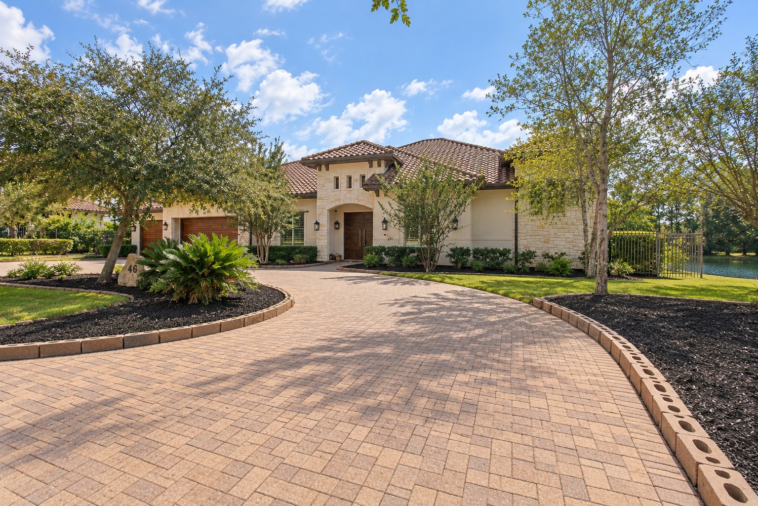 Impressive horseshoe-shaped paver driveway creates a grand entrance, surrounded by beautifully landscaped grounds and offering an elegant welcome to this luxury estate.